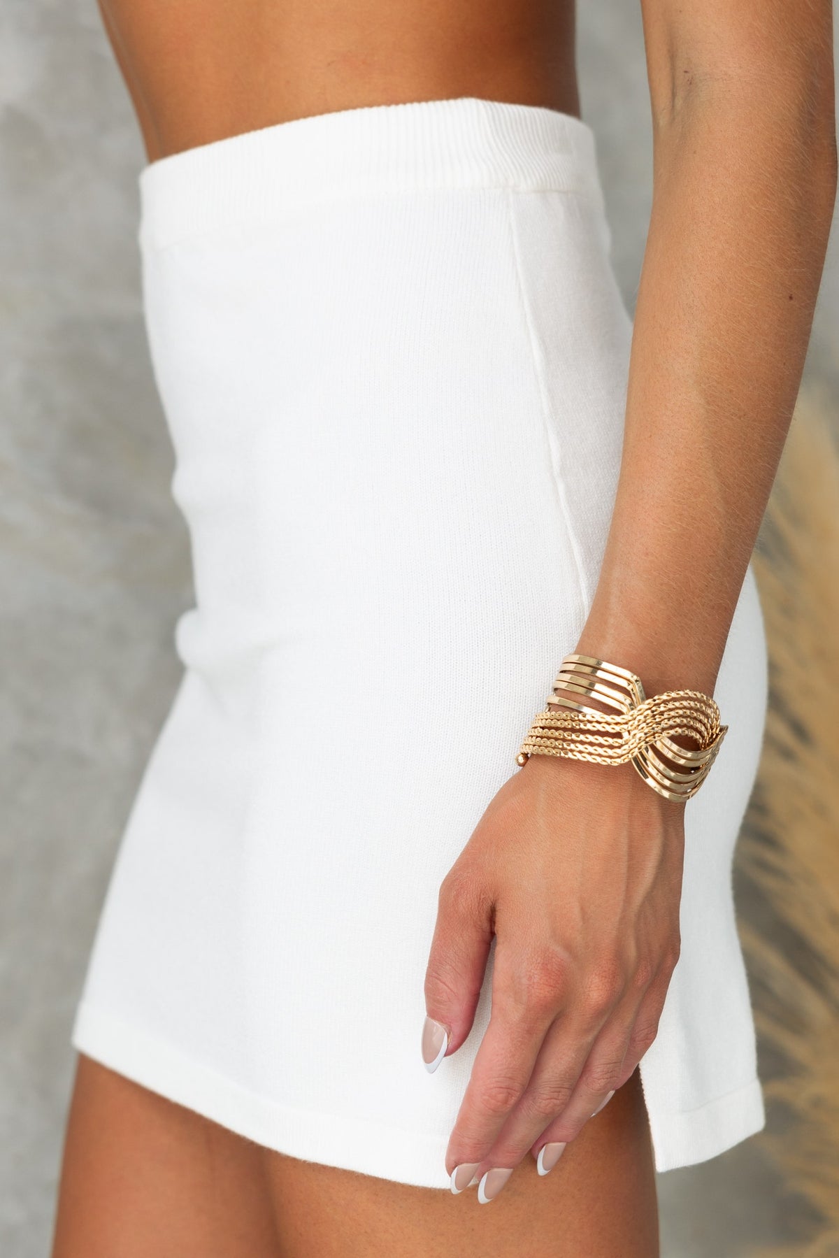 Close-up of Yettie Skirt, a mid-high waist white ribbed knit skirt featuring a side split and elastic waistband.