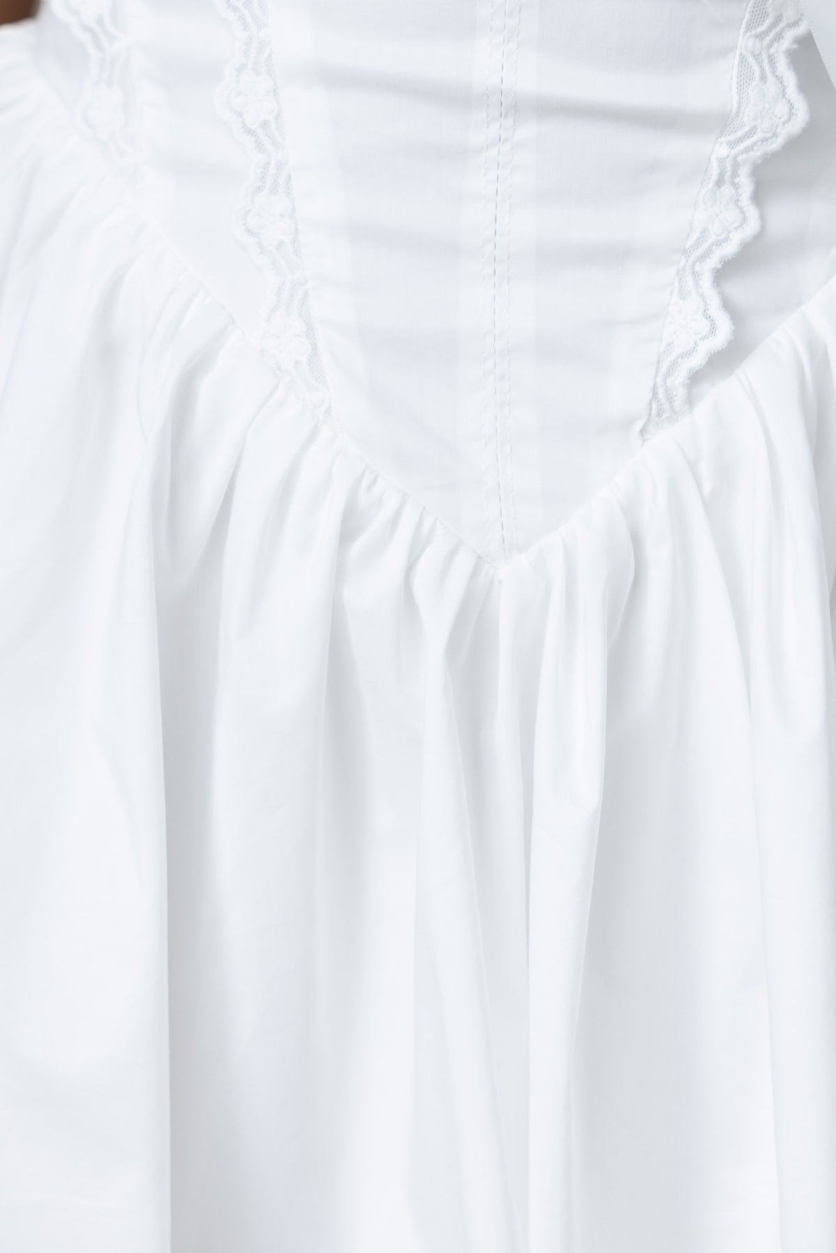 Elegant white Cevallo dress featuring tie detail at bust and lace accents throughout for a sophisticated look.