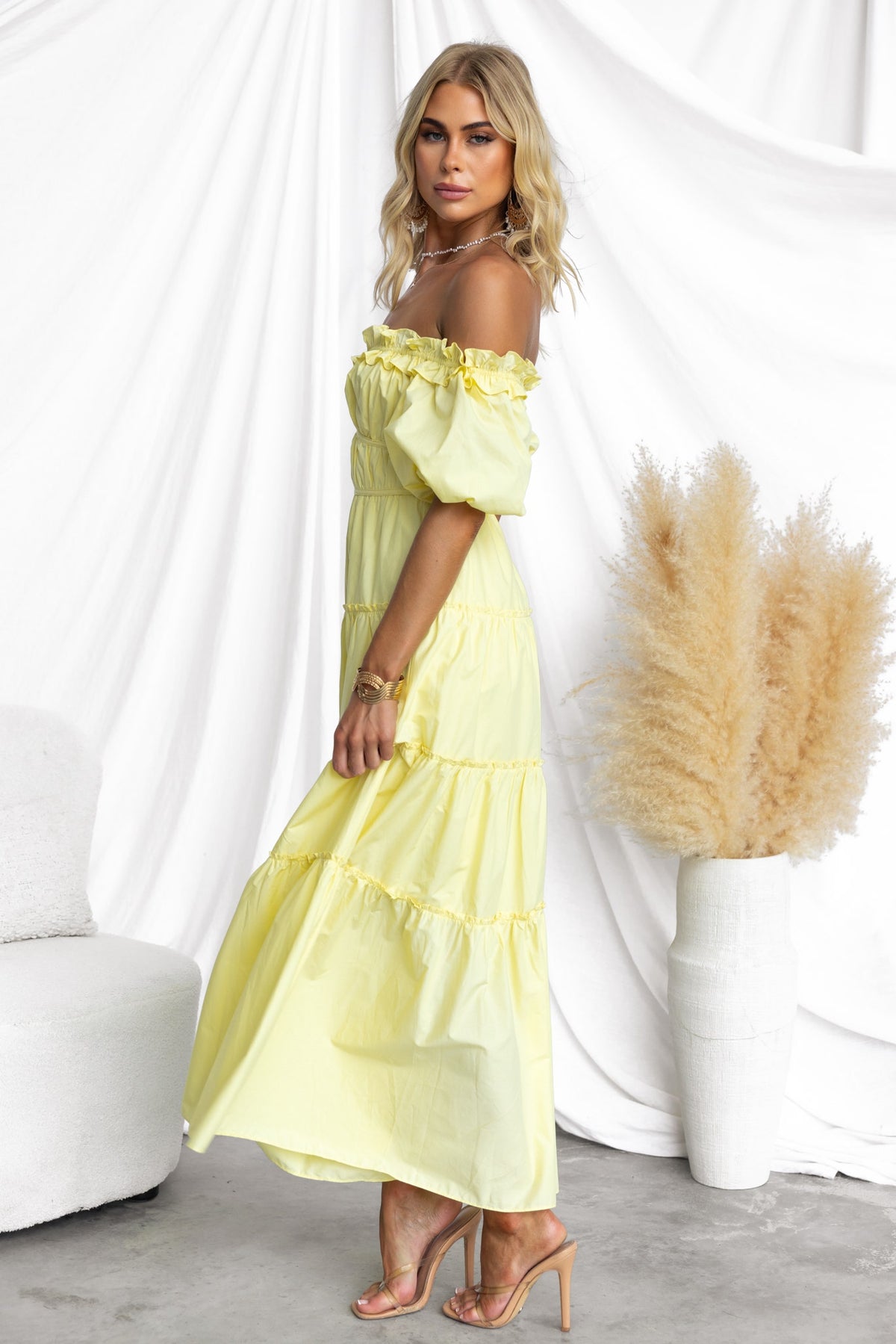 Side view of a model wearing a yellow off-shoulder Archer Maxi Dress with tiered layers and a relaxed fit.