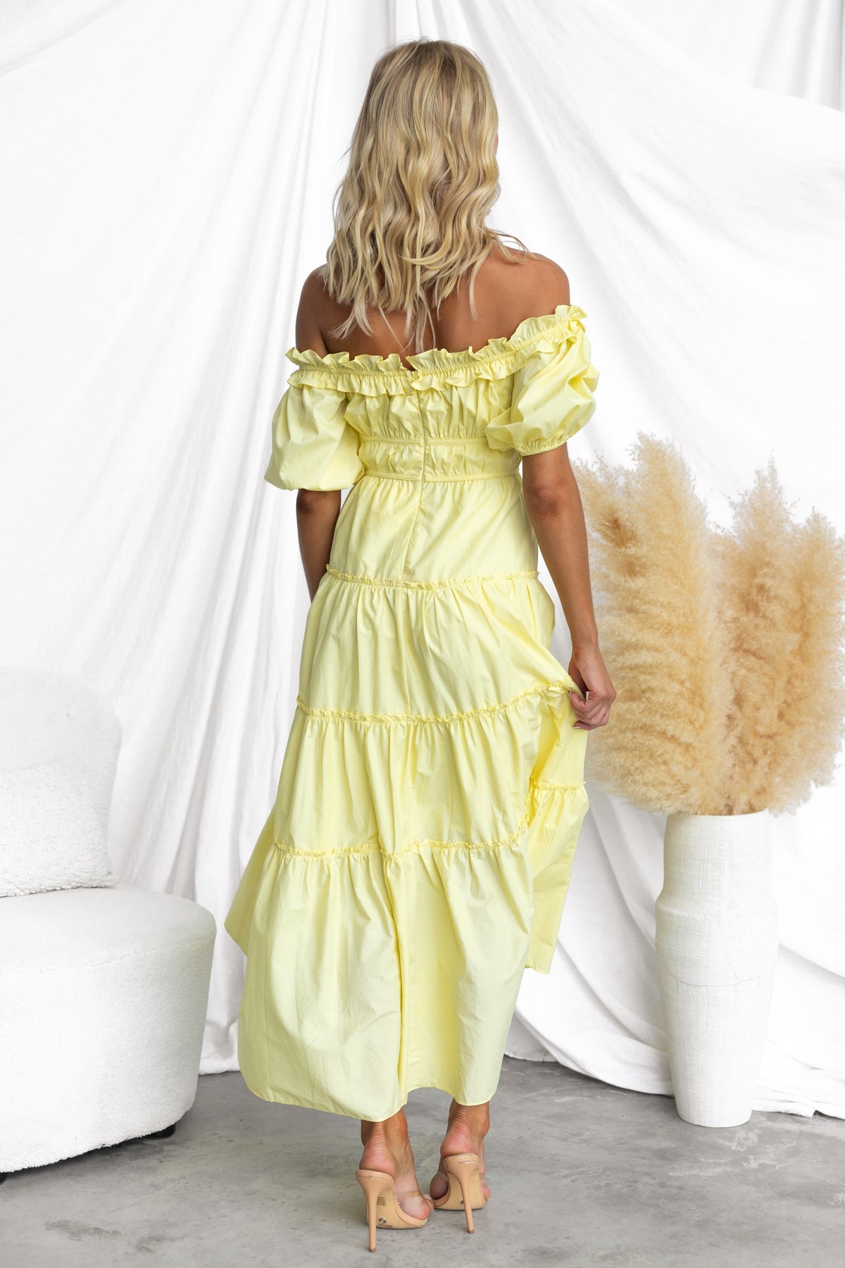 Back view of a woman in a yellow off-shoulder Archer Maxi Dress, featuring tiered design and a relaxed fit.