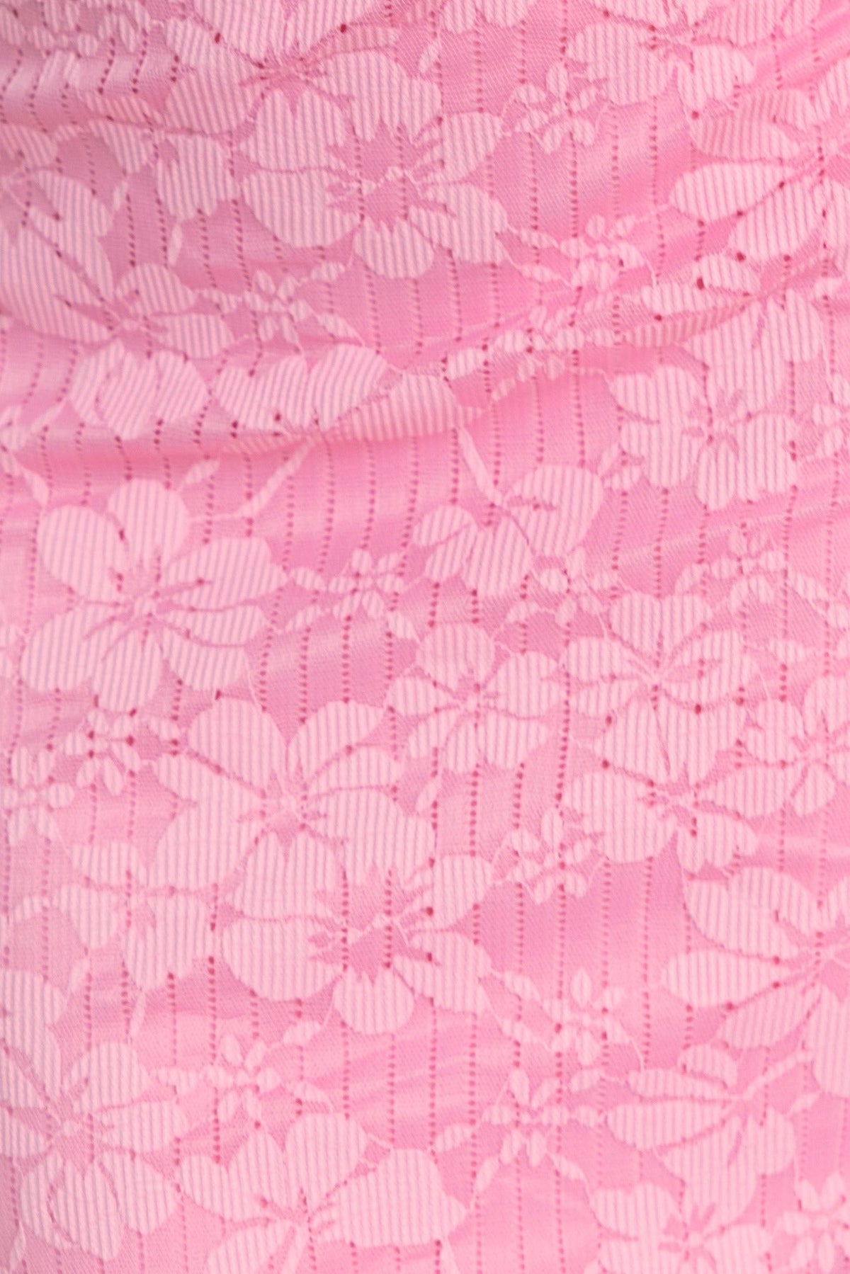 Close-up of pink lace fabric with floral pattern, showcasing a delicate and elegant design for fashion apparel.