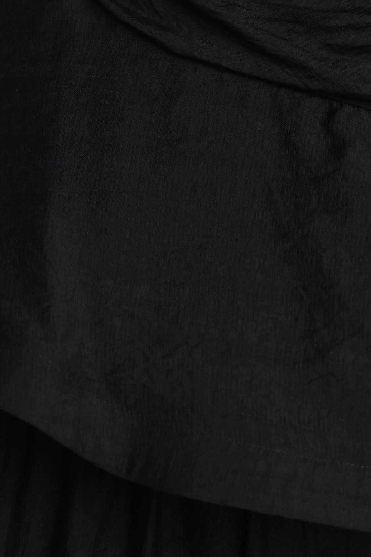 Close-up of black draping material from a one-shoulder maxi dress, showcasing its soft texture and elegant design.