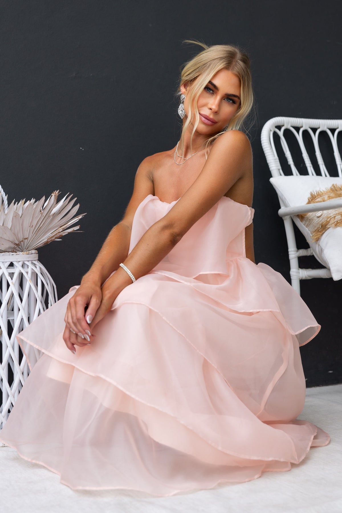 Model wearing a Lilianna Maxi Dress in soft pink chiffon, showcasing its strapless design and layered ruffles.