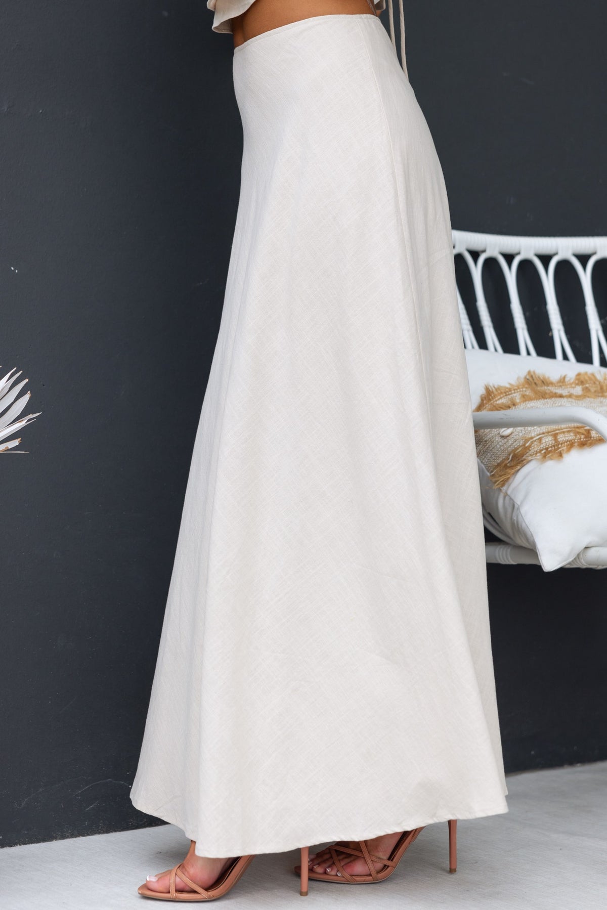 A side view of the Shana Maxi Skirt in light beige, featuring a mid-high waist and flowing silhouette.