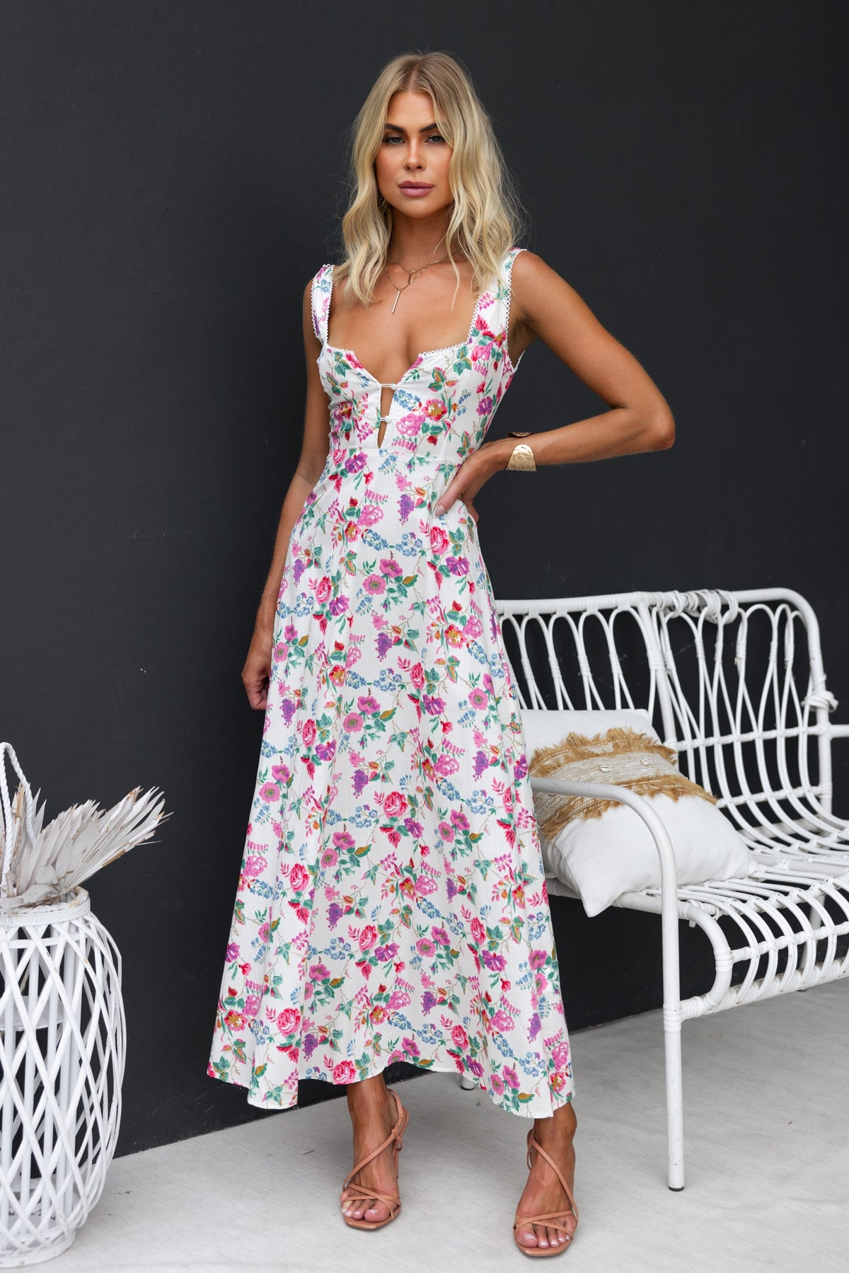 Model wearing Keely Midi Dress, a floral print midi dress with buttons and tie, against a stylish backdrop.
