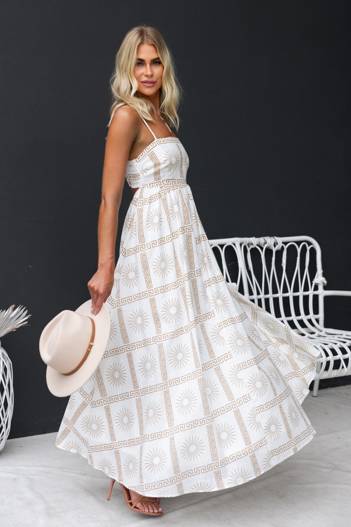 Bordeline Maxi Dress featuring an abstract print with adjustable straps and cut-out back, styled with a sun hat.