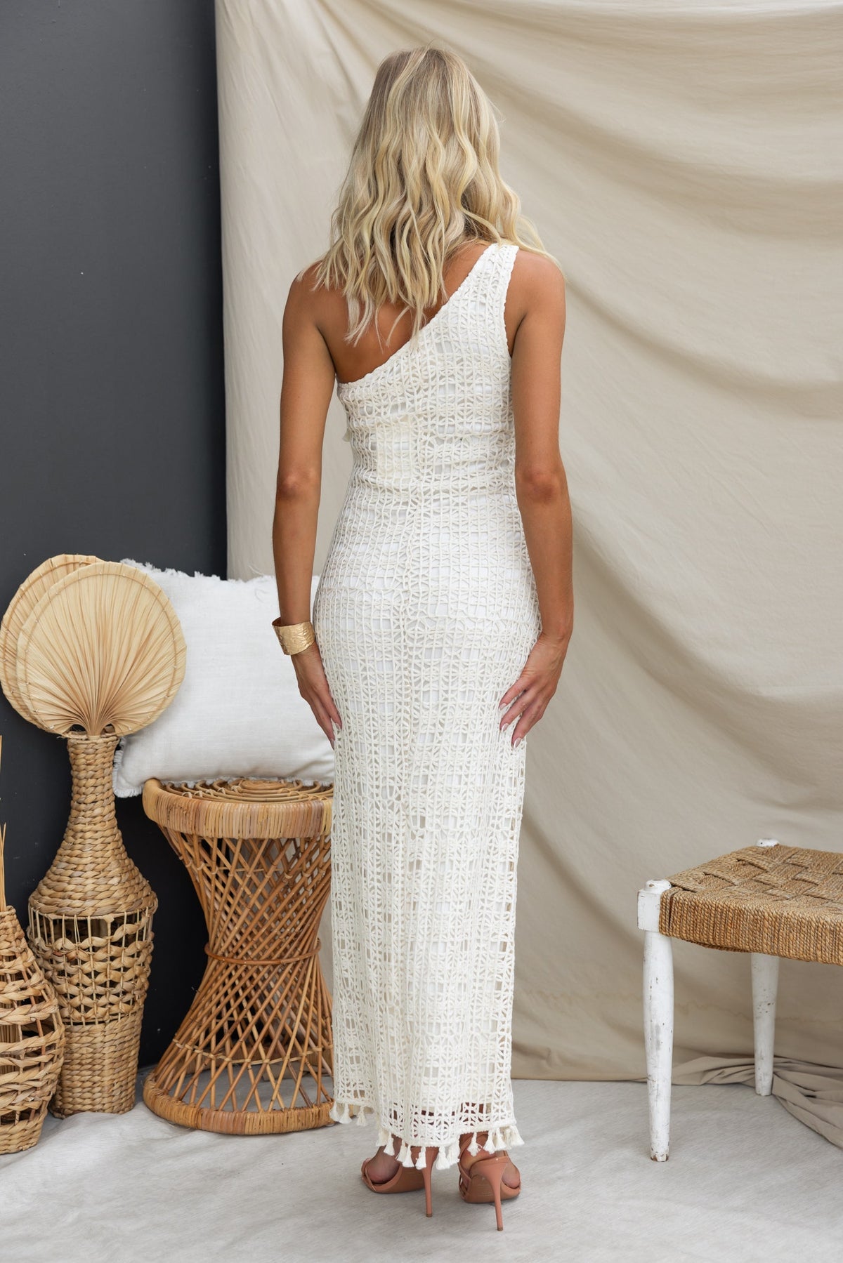 Back view of a woman wearing a white crochet Cyprus maxi dress with one-shoulder design, showcasing a stylish and elegant look.