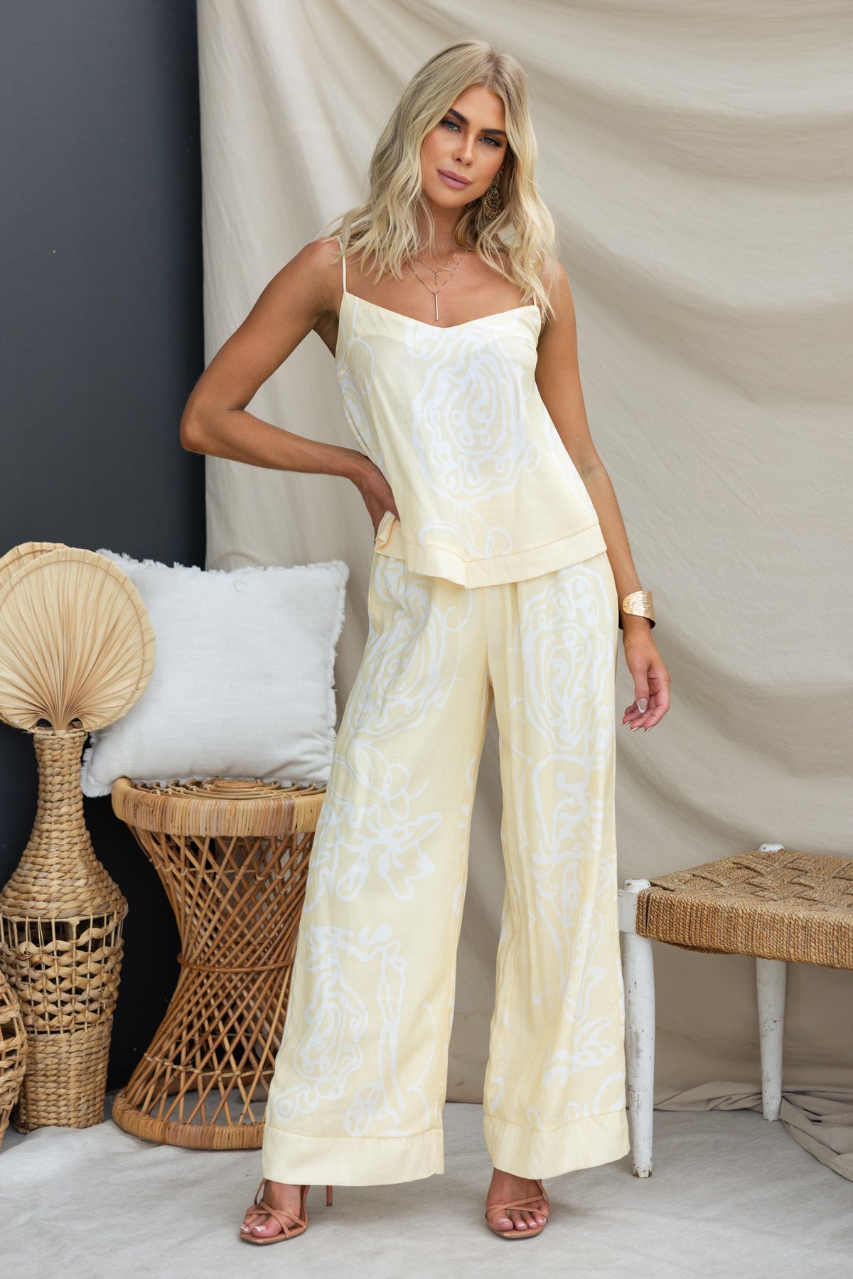 Model showcasing the Izobelle Set with a flowing top and mid-high waist pants in a soft yellow linen look.