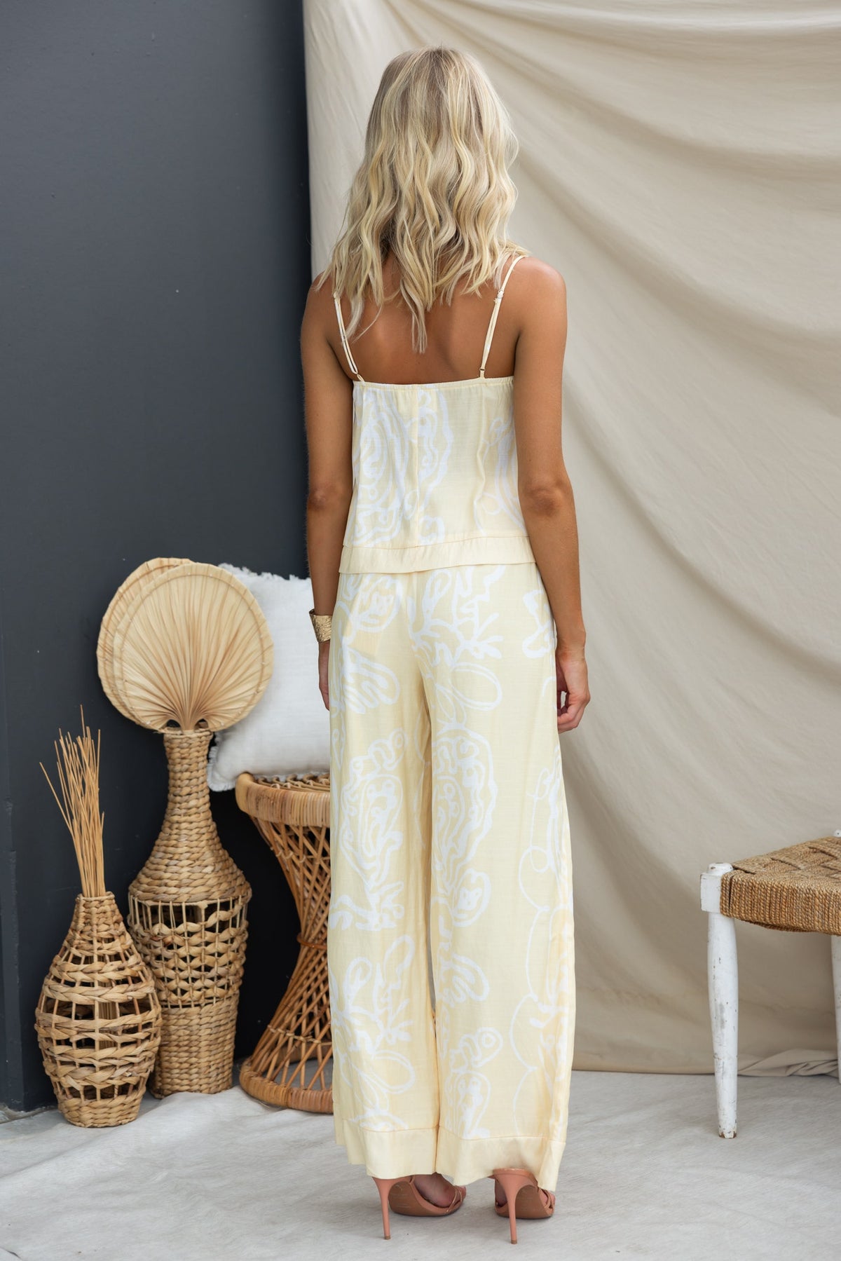 Back view of a woman wearing the Izobelle Set featuring a printed top with adjustable straps and mid-high waist pants.