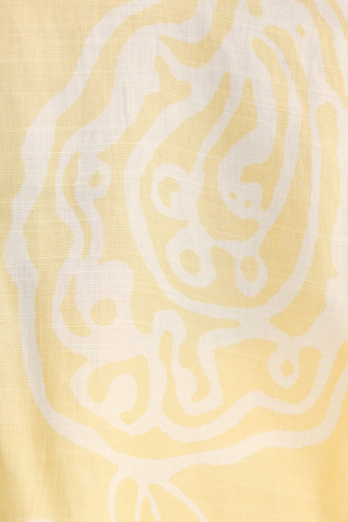 Close-up of Izobelle Set fabric featuring a soft yellow background with white abstract patterns.