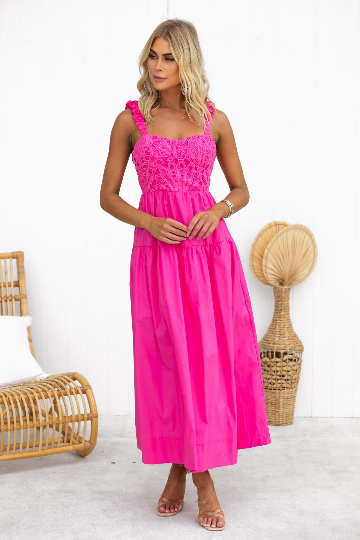 Bright pink Neisha Maxi Dress with lace detailing and elastic straps, styled for a tropical setting.