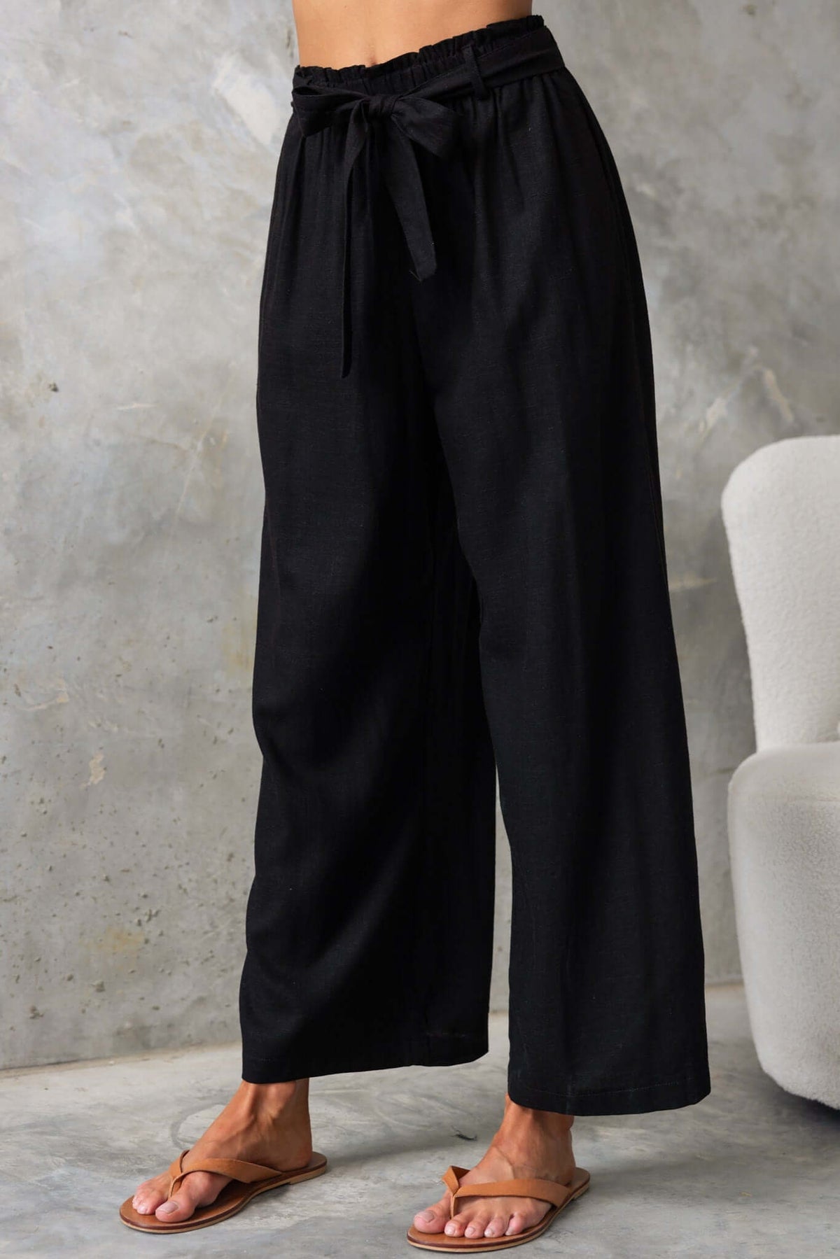Umali Pants in black with mid-high waist, elastic waistband, removable tie, and pockets, perfect for summer wear.