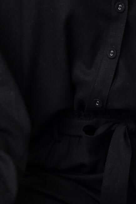 Close-up detail of the Umali Pants featuring a removable tie and buttoned shirt in a linen-like fabric.