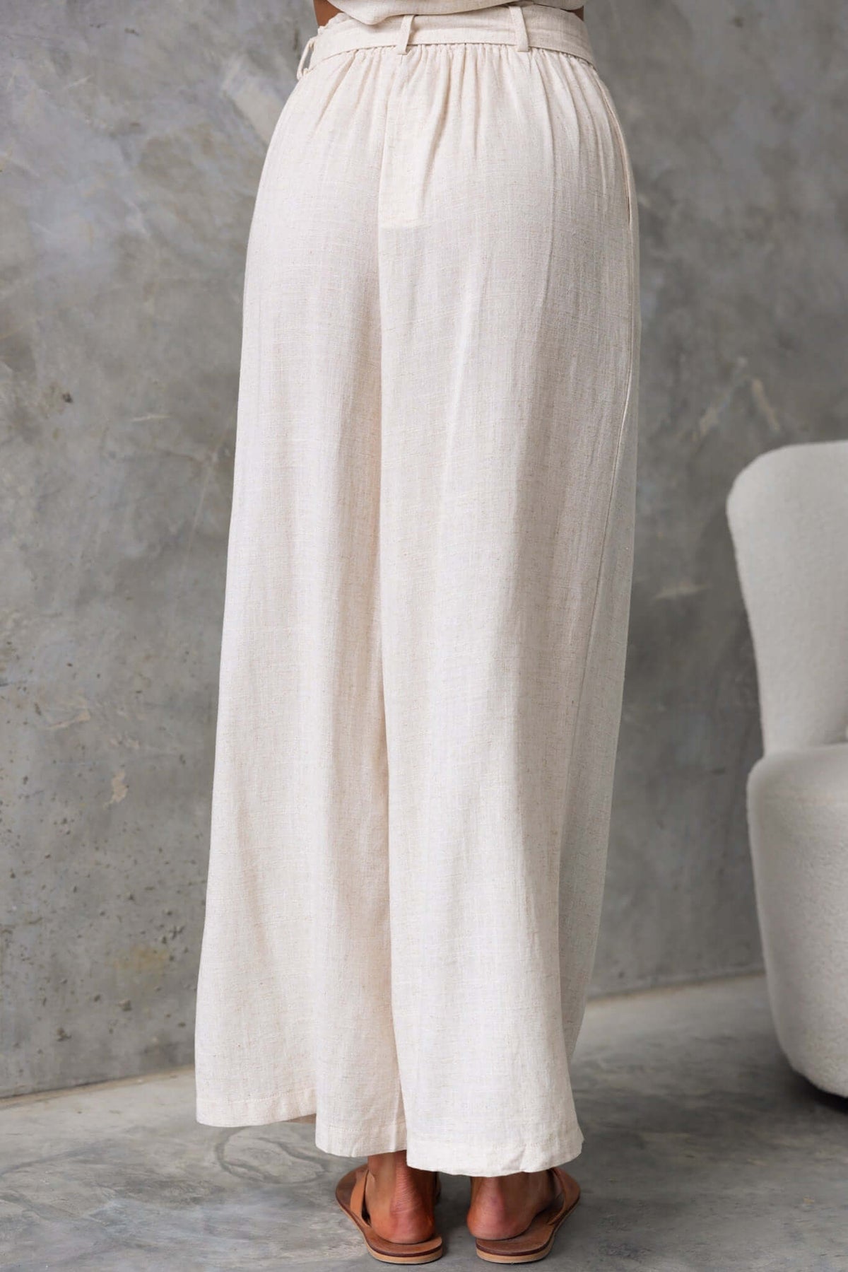 Back view of Umali Pants, featuring a mid-high waist fit, elastic waistband, and linen texture in a light color.