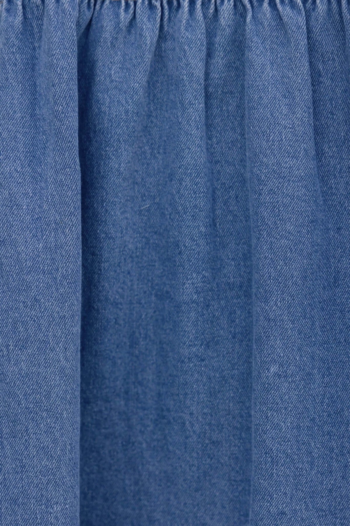 Close-up of blue denim fabric with gathered texture, showcasing the material of the Tulsa Denim Dress.