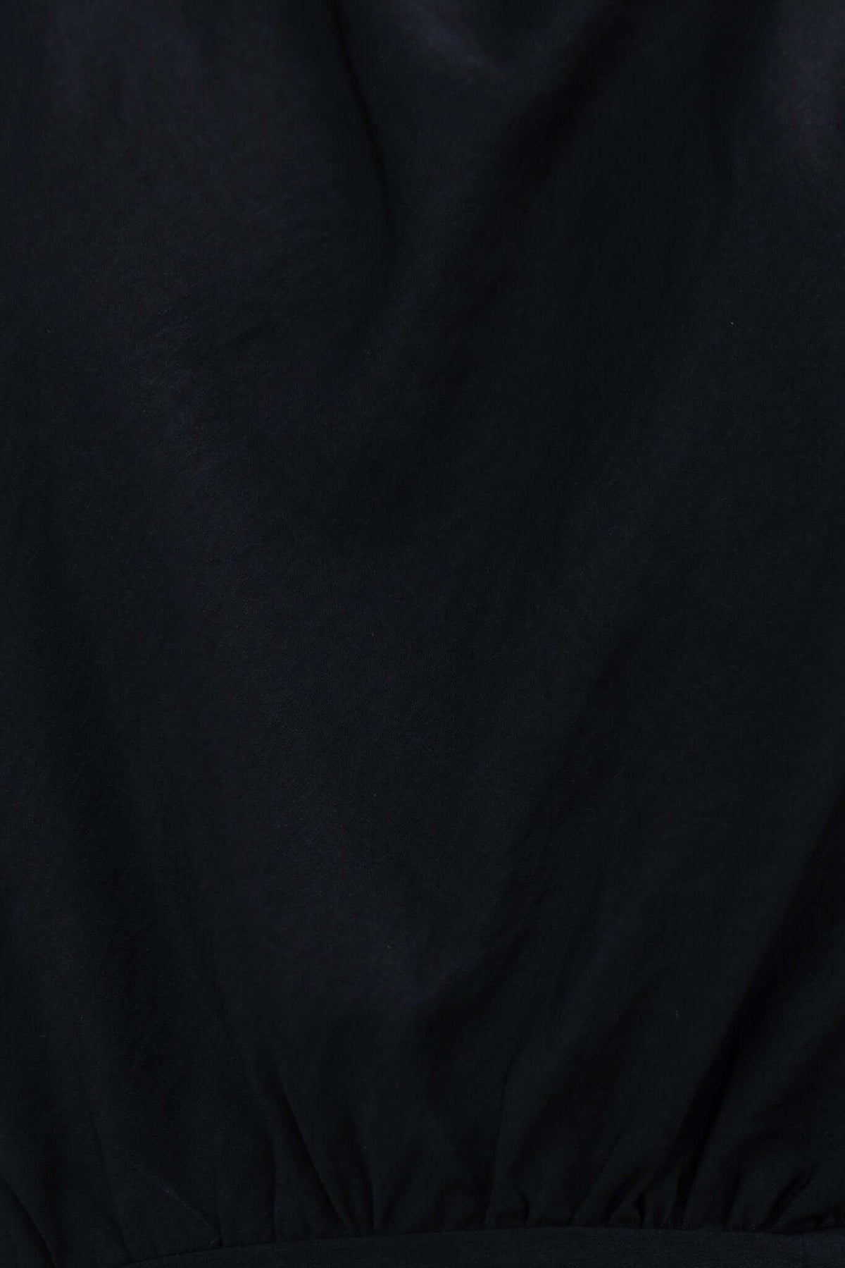 Close-up of the fabric texture of the Torre Dress, a sleek black attire featuring a stretch material design.