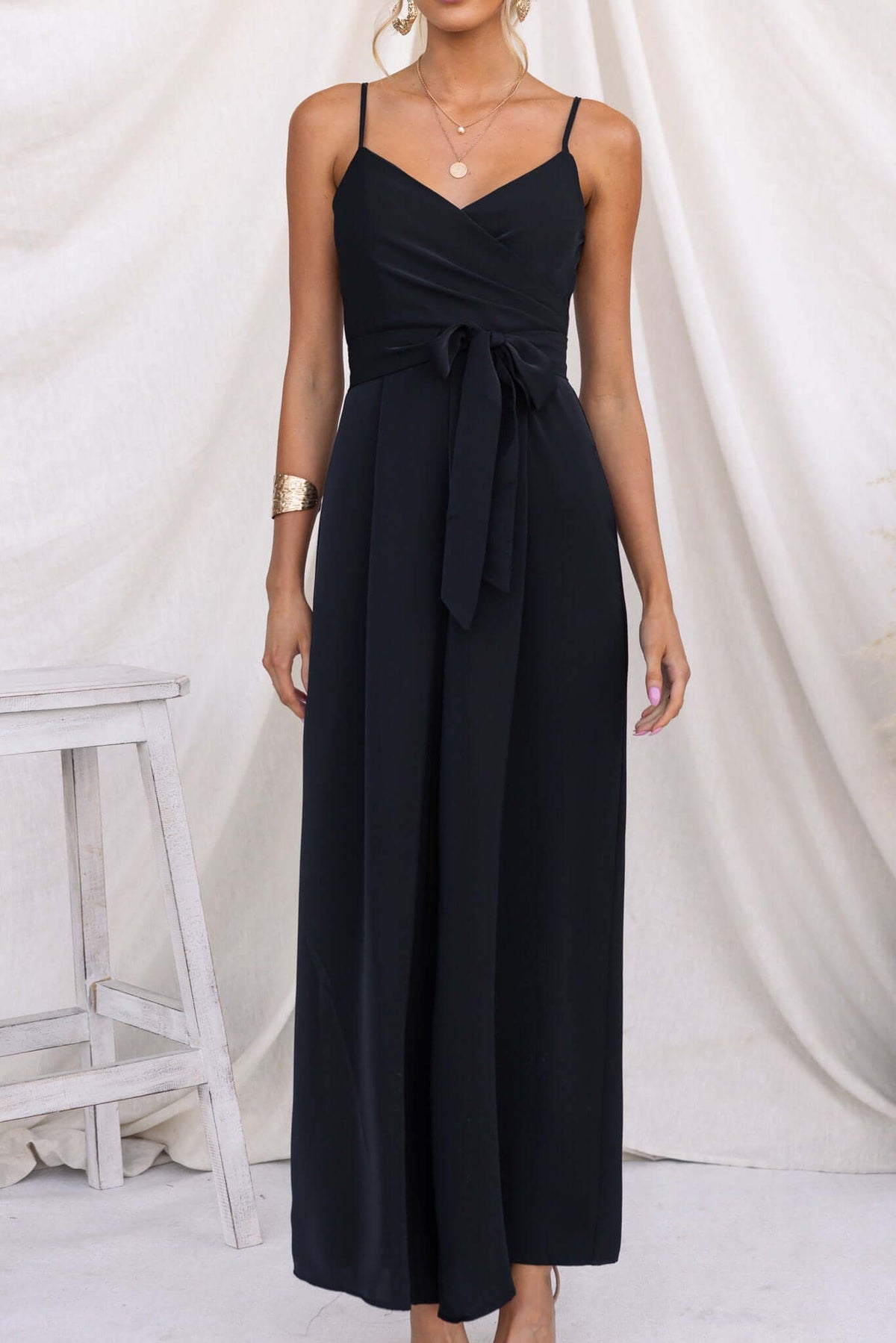 Black Couver Jumpsuit with adjustable spaghetti straps and removable belt, showcased by a model.