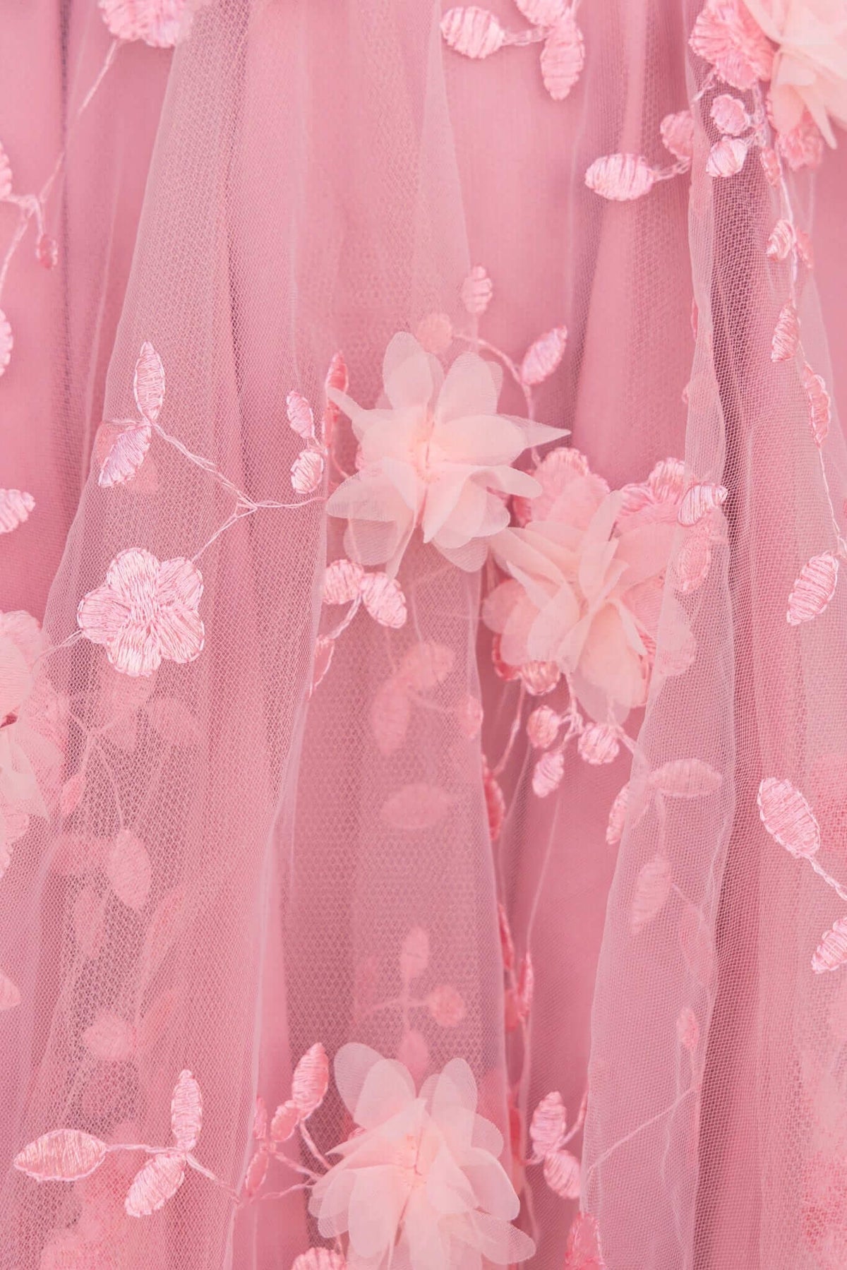 Close-up of pink lace dress fabric featuring floral embroidery and tulle details, perfect for summer wear.