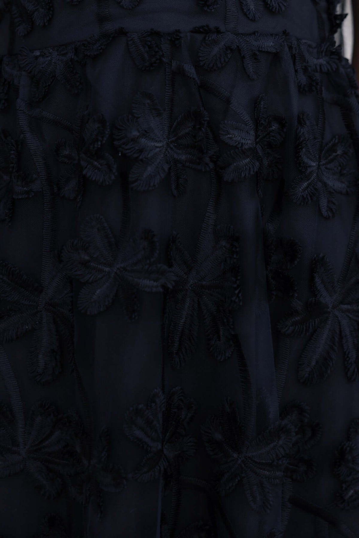 Close-up of embroidered tulle fabric on Xaria Maxi Dress, featuring intricate leaf patterns in black.