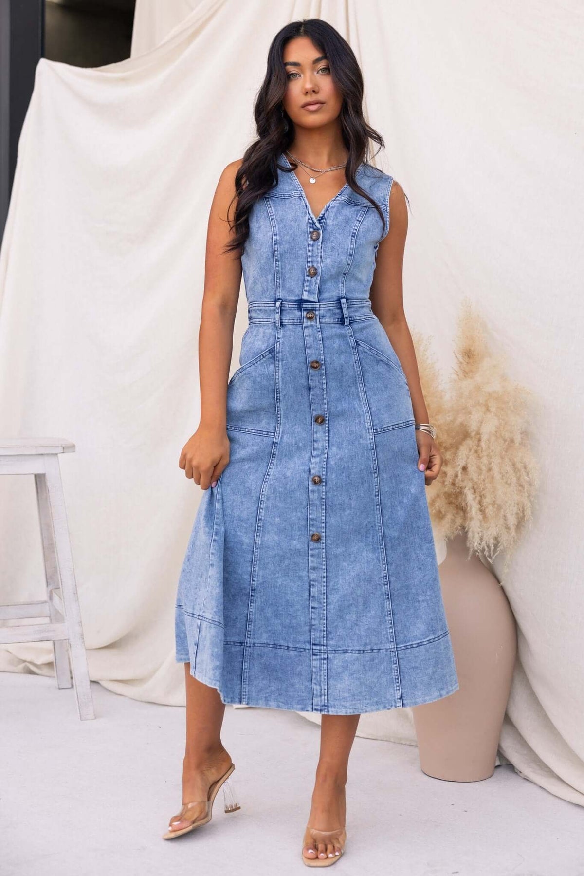 Kerrie Denim Midi Dress featuring a V-neckline, buttons, and pockets, styled in light blue denim with a flattering fit.