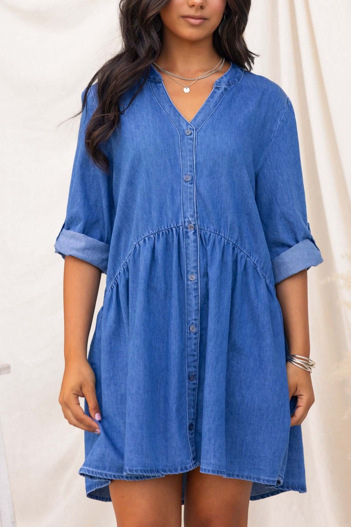 Gracie Denim Dress featuring a V-neckline and button-up front in a relaxed fit, made from 100% cotton.