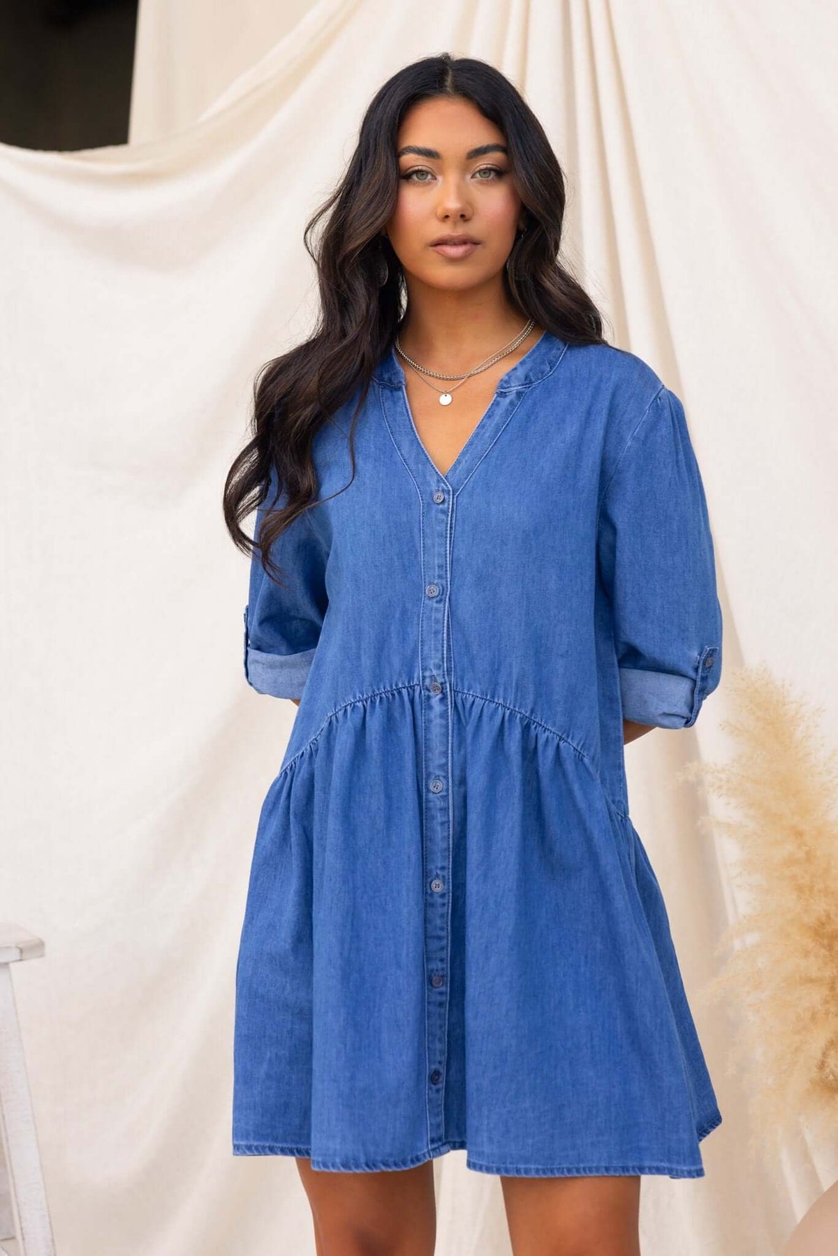 Model wearing a Gracie Denim Dress with V-neckline and button-up front, showcasing a relaxed fit and denim design.