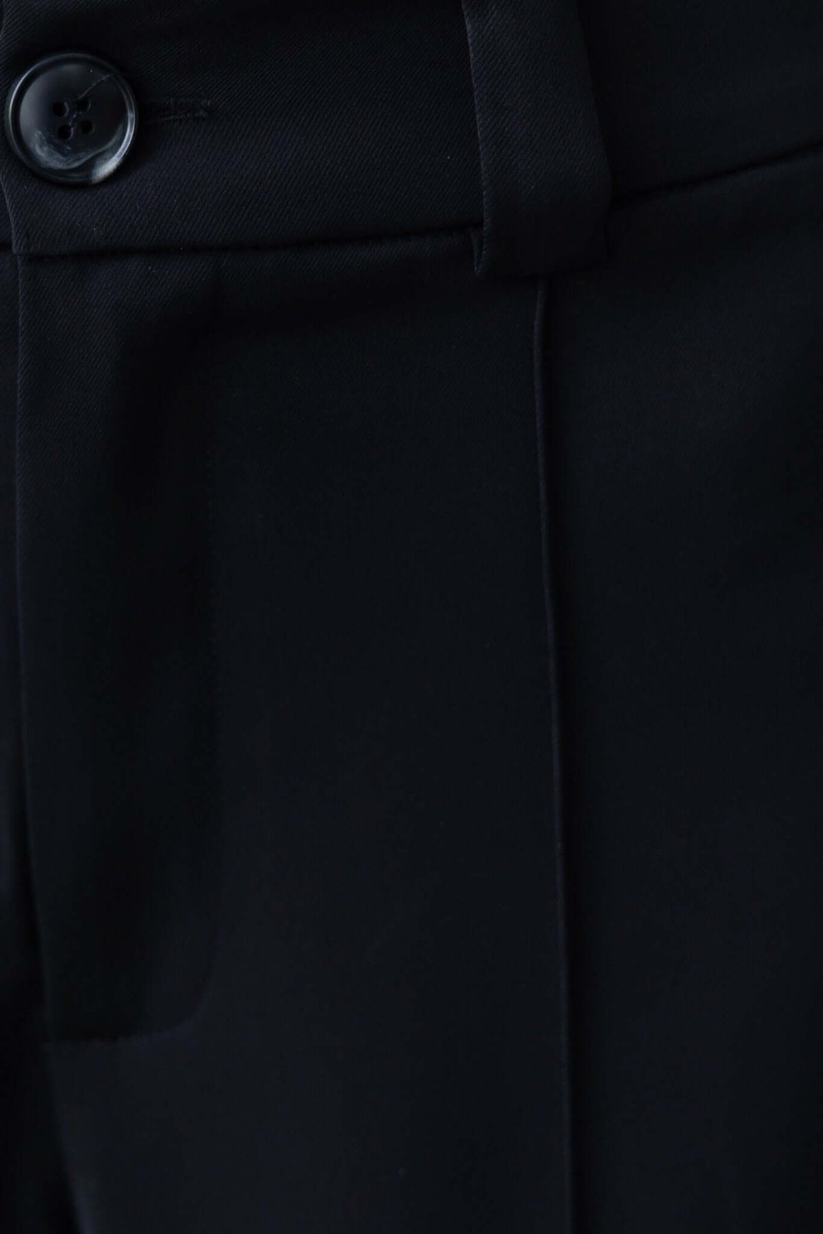 Close-up of black Columbus Pants featuring a mid-high waist and button detail, non-lined design.