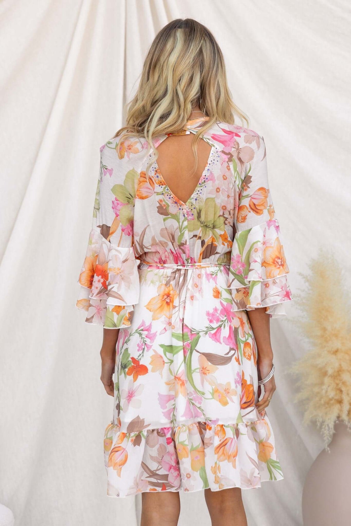 Back view of Fools Gold Wrap Dress featuring floral print, ruffled sleeves, and a tie waist.