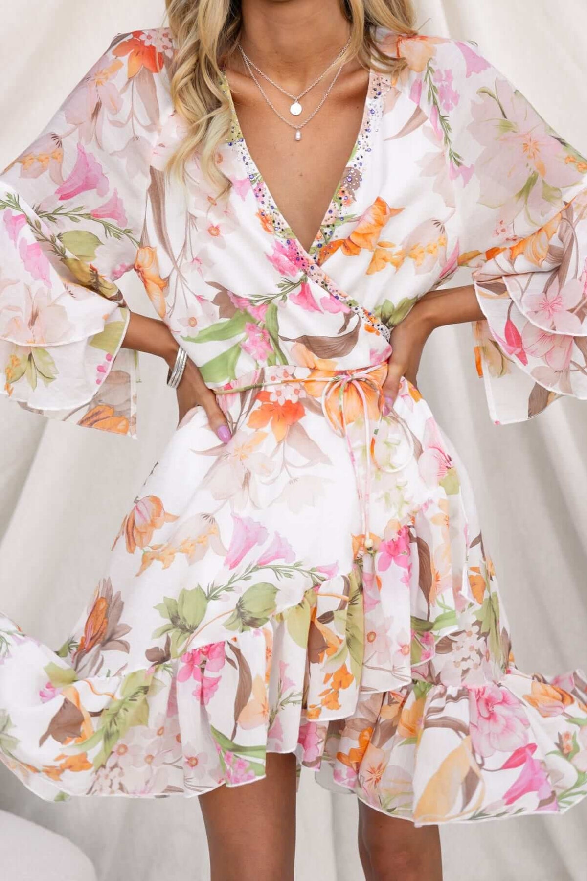 Floral Fools Gold wrap dress with V-neckline, bell sleeves, and a ruffled hem, featuring gem embellishments.