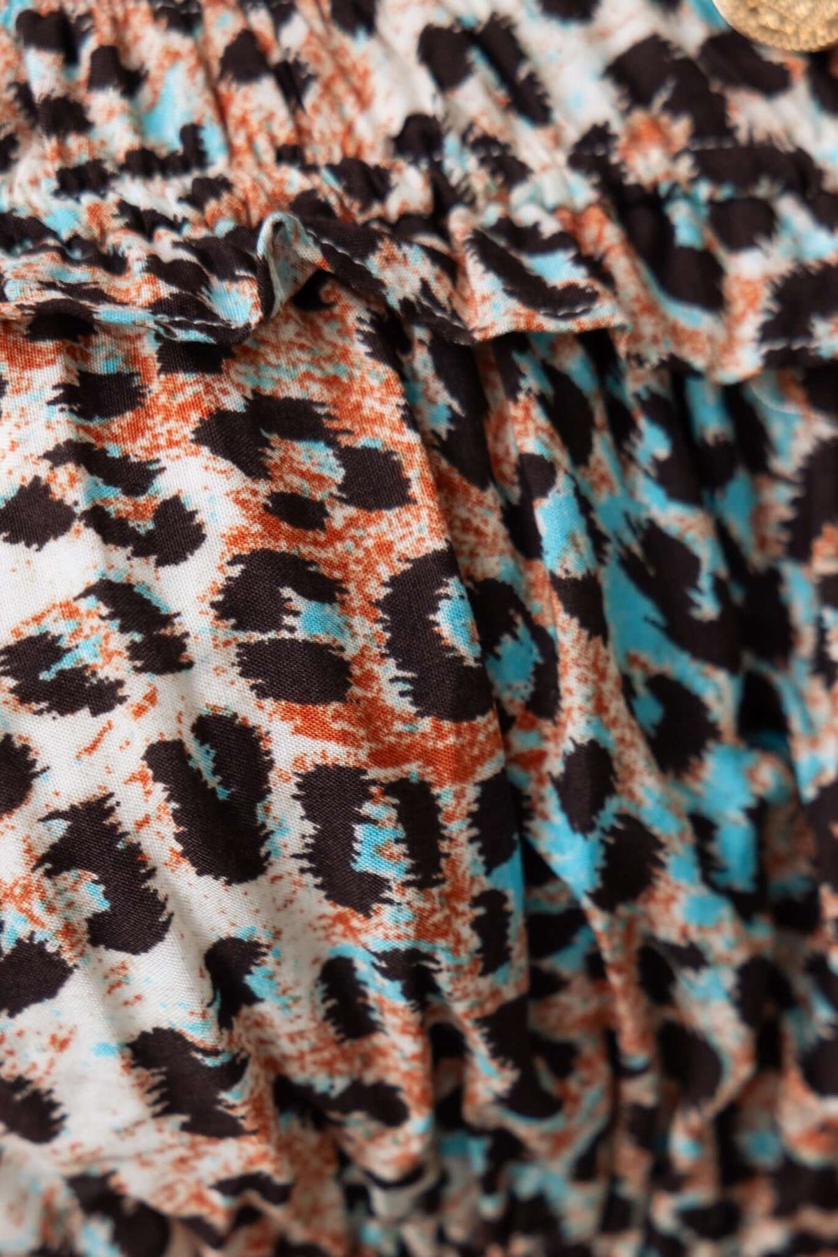Close-up of Abeni Jumpsuit fabric featuring a stylish leopard print in orange, black, and blue shades.
