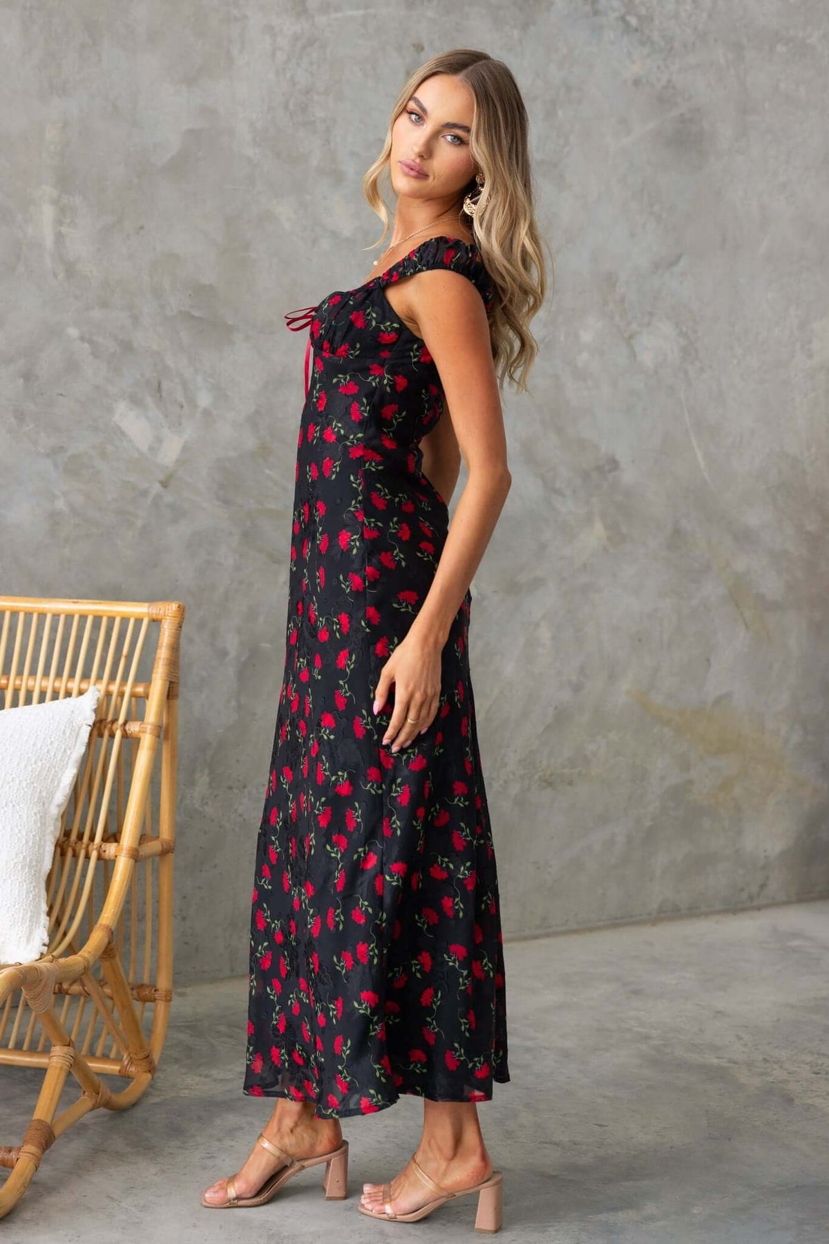 Black floral maxi dress with side cutouts and bow detail, styled with block heels.