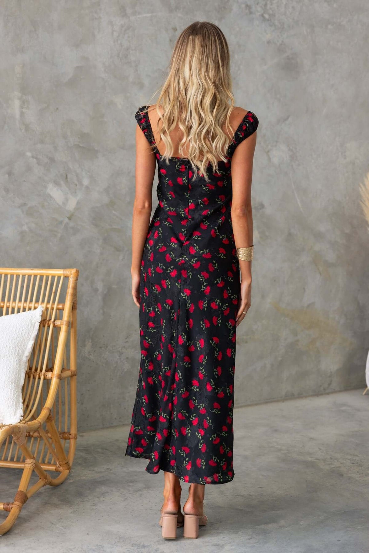 Back view of a black maxi dress with floral print, featuring a fitted silhouette and stylish straps.