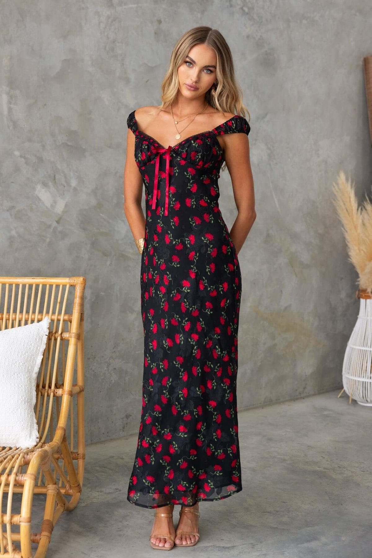 Black floral maxi dress with off-shoulder sleeves and red ribbon detail, perfect for summer wear.