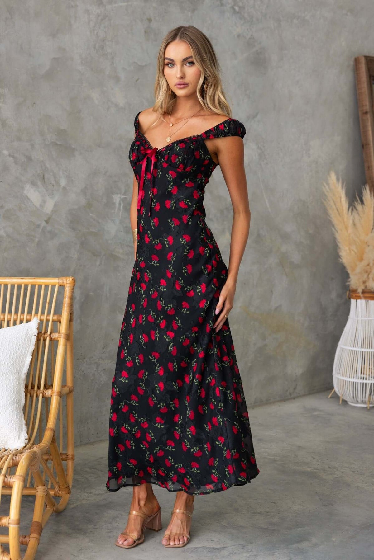 Black maxi dress with red floral print and off-shoulder design, perfect for summer occasions.