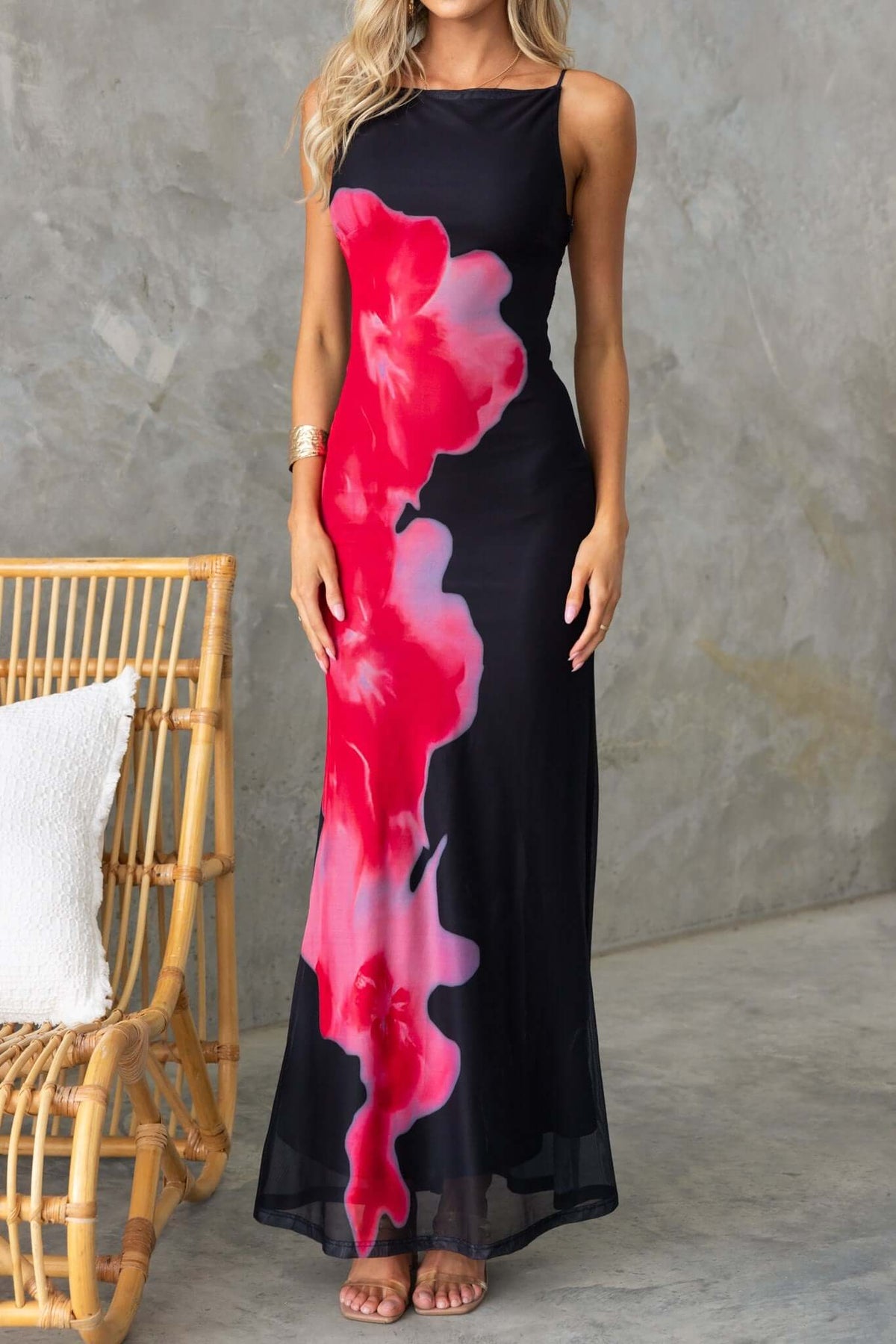 Black maxi dress with bold pink floral design, perfect for summer occasions.