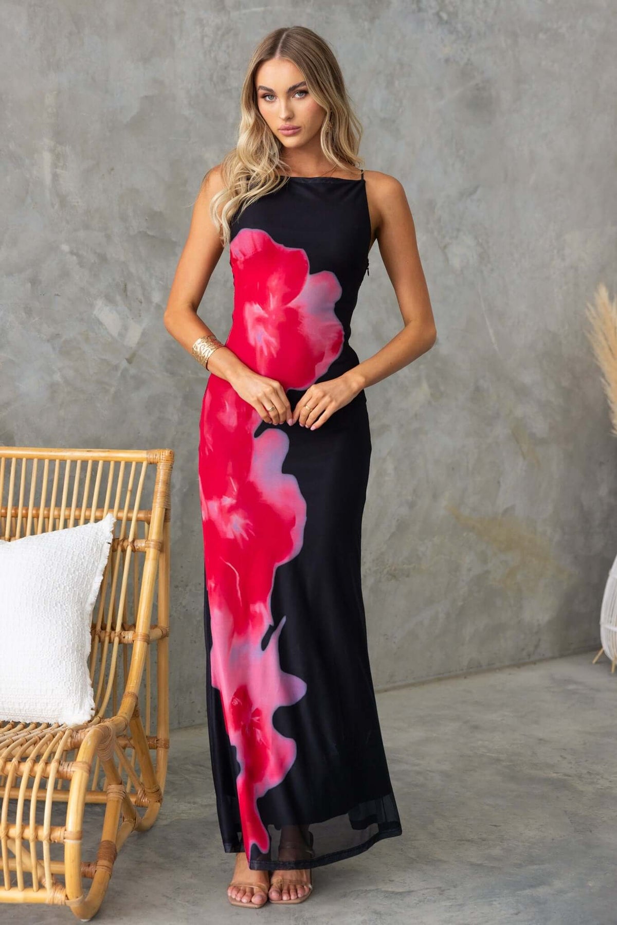 Model wearing black maxi dress with pink floral design, showcasing a stylish summer look.