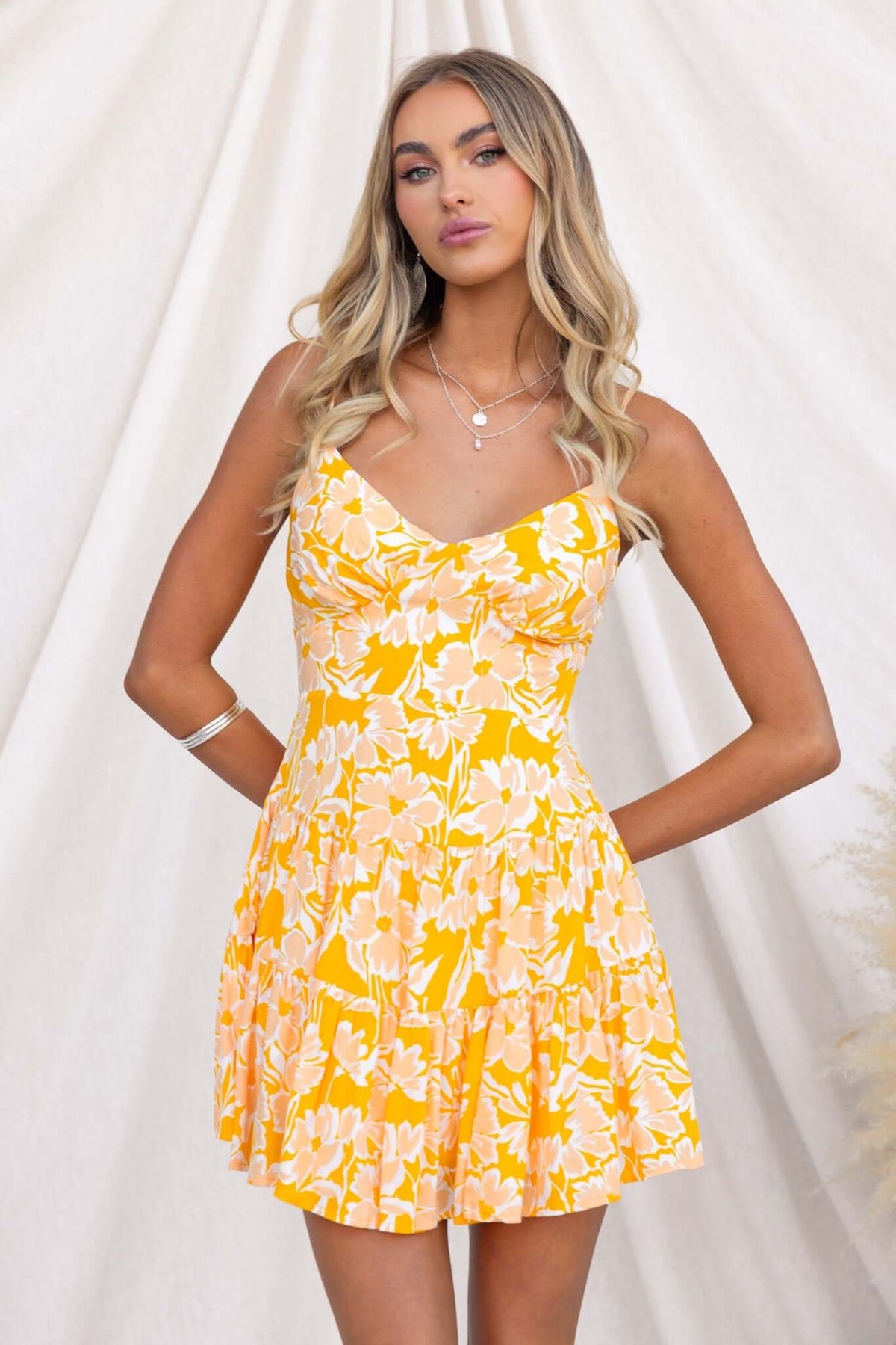 Model wearing the Everton Dress, a yellow floral summer dress with adjustable straps and a flared skirt.