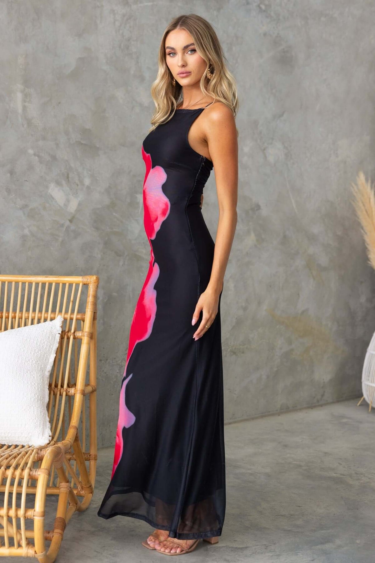 Model wearing a black maxi dress with colorful floral patterns, showcasing adjustable straps and a chic silhouette.