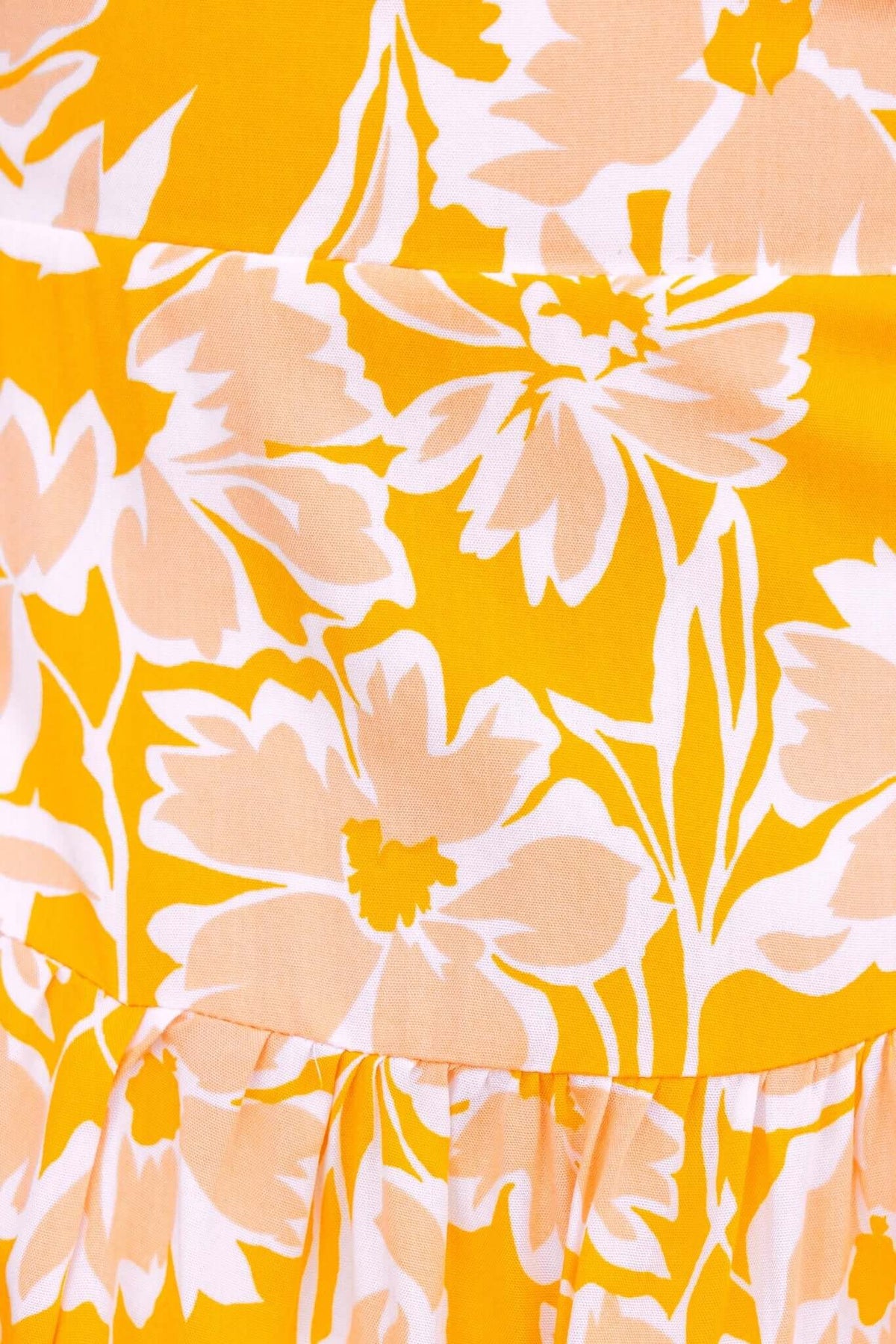 Close-up of yellow floral pattern fabric on Everton Dress, featuring elegant blooms in soft white and peach tones.