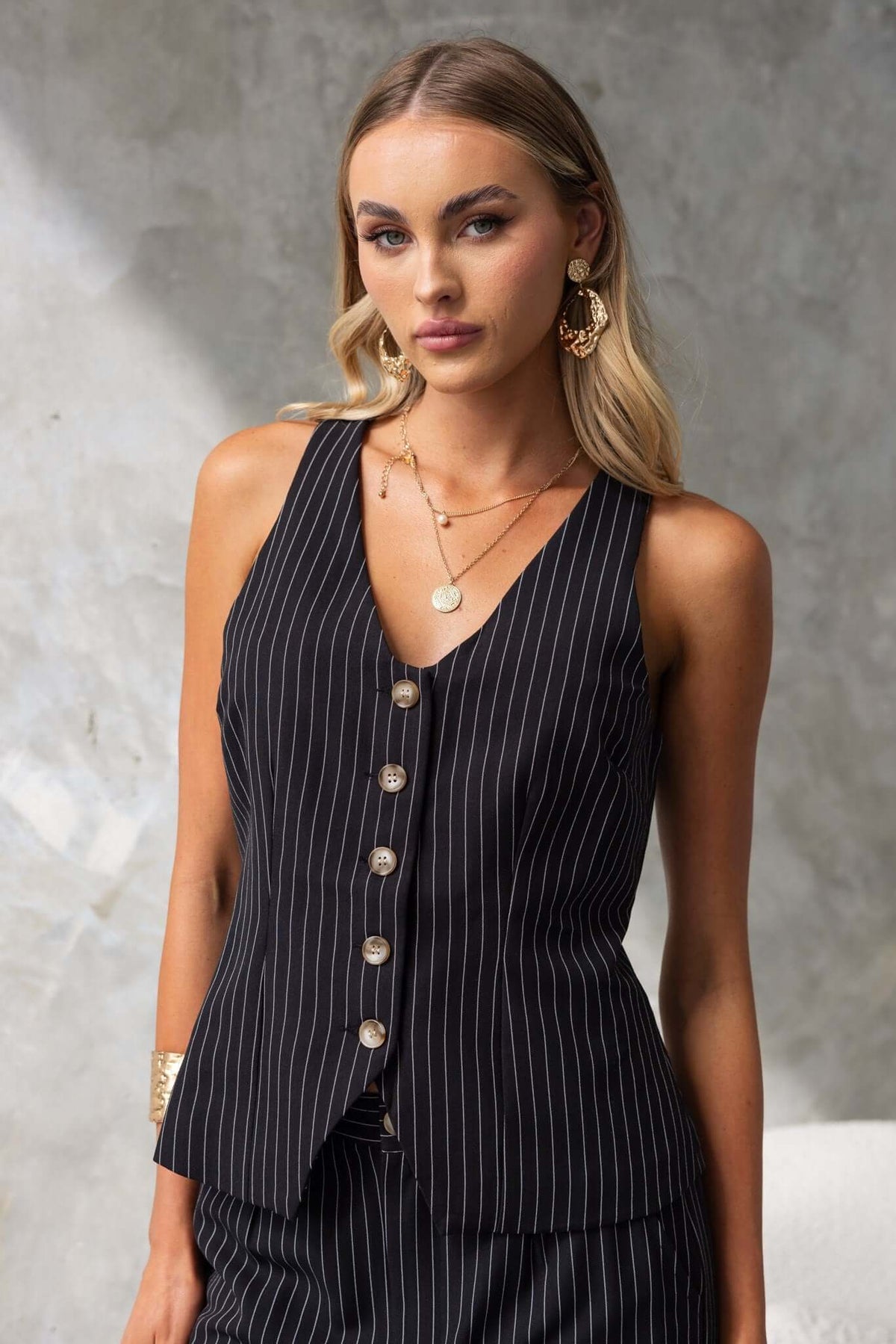 Black striped sleeveless vest with buttons, worn by a woman, perfect for summer fashion.
