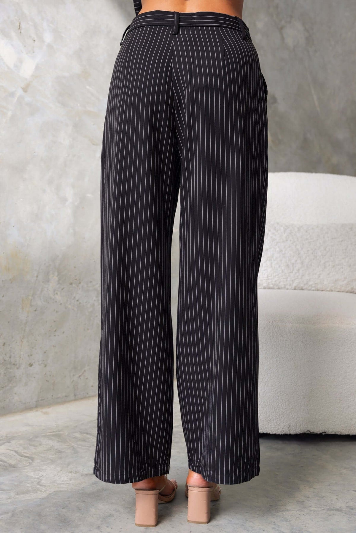 Back view of black mid-high waist striped pants with wide legs and pockets, perfect for summer wear.