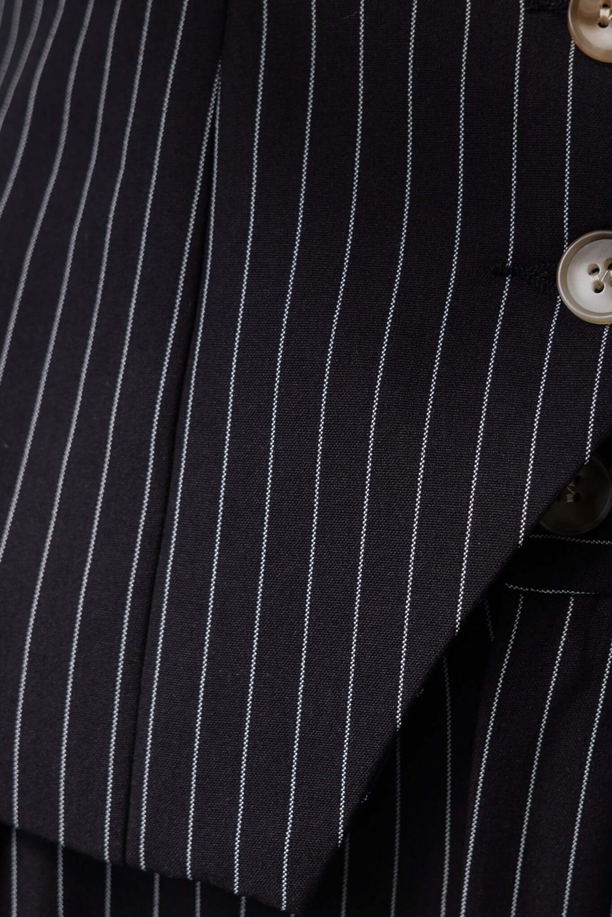 Close-up of black pinstripe fabric showcasing buttons and tailored design for stylish summer pants.