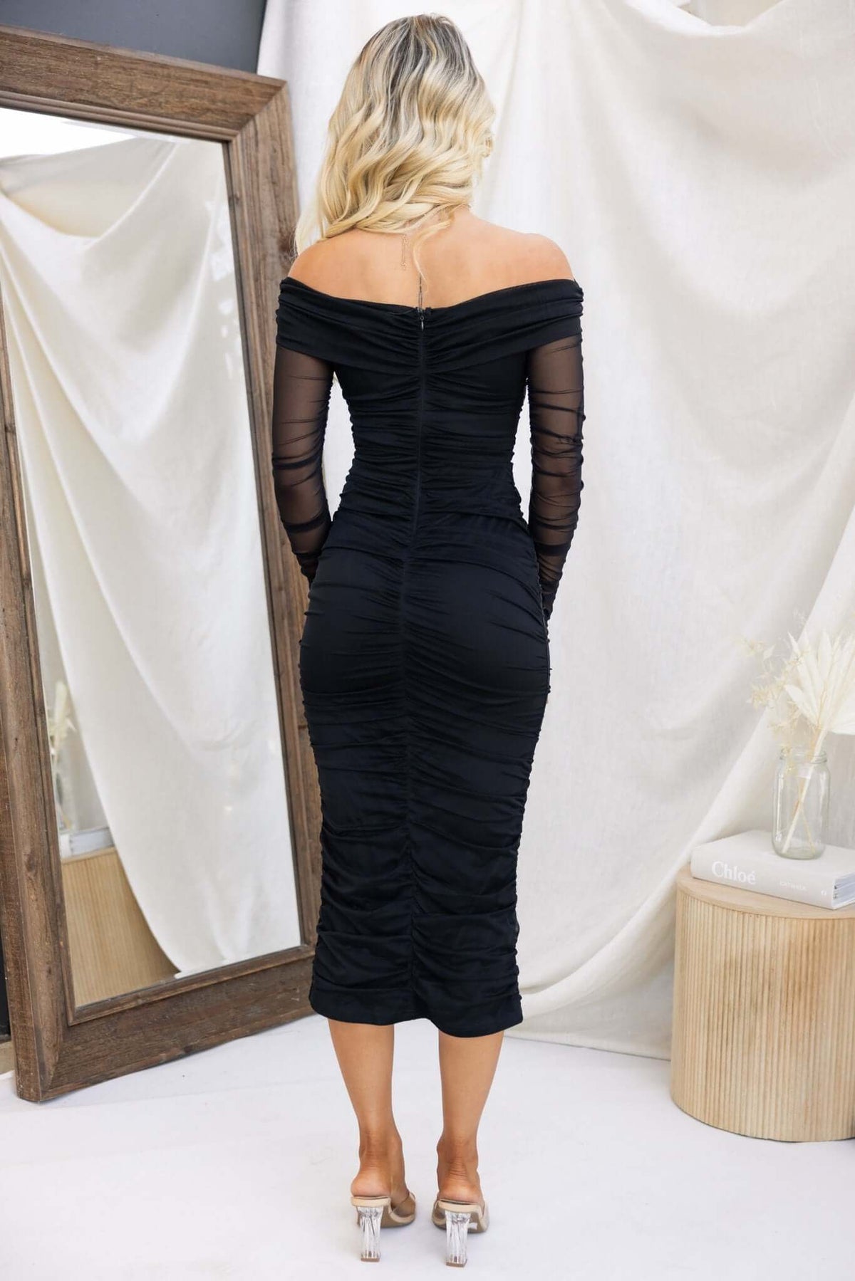 Back view of Hilton Midi Dress featuring an off-shoulder design, ruched fabric, and long sheer sleeves.