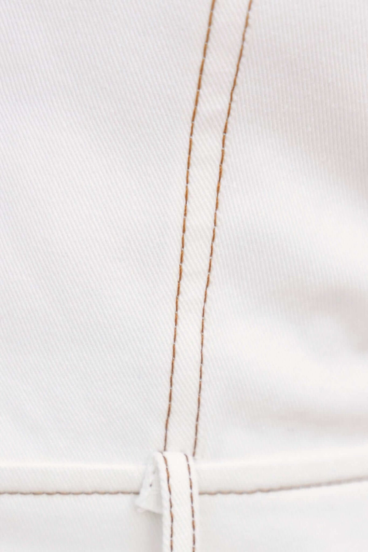 Close-up of white fabric with detailed stitching, showcasing the quality of a denim playsuit.