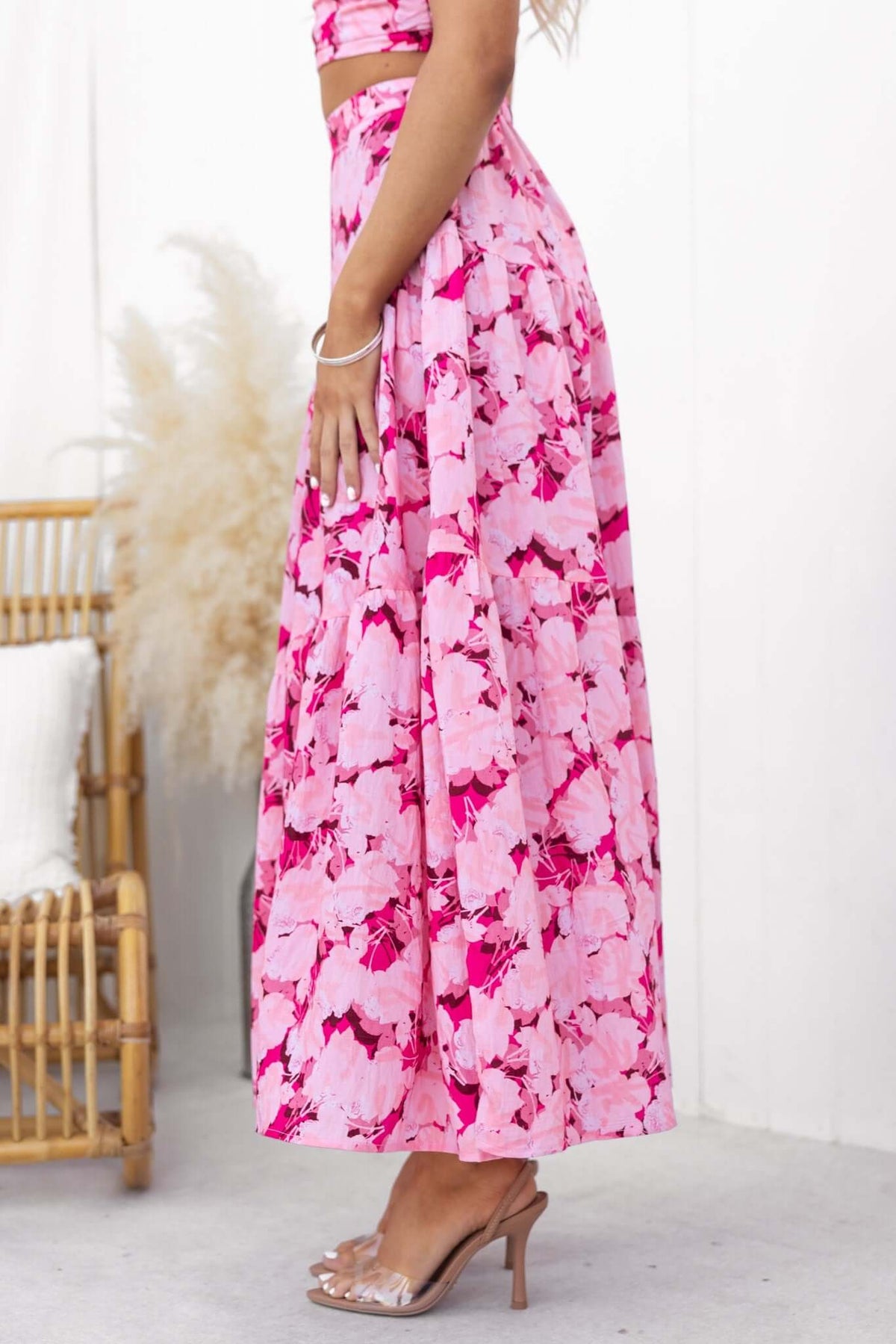 Side view of Peachy Days Maxi Skirt in pink floral print, featuring an elastic waist, styled with heels.