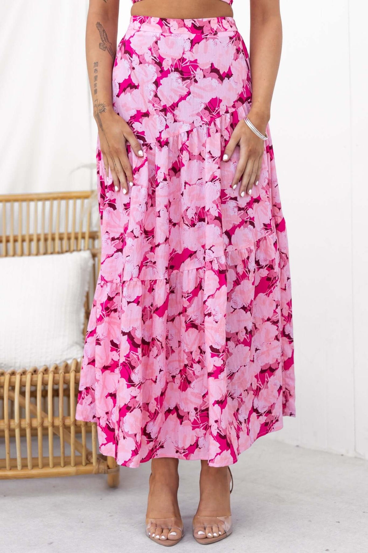 Model wearing Peachy Days Maxi Skirt in vibrant pink floral pattern, showcasing elastic waist and flowy design.