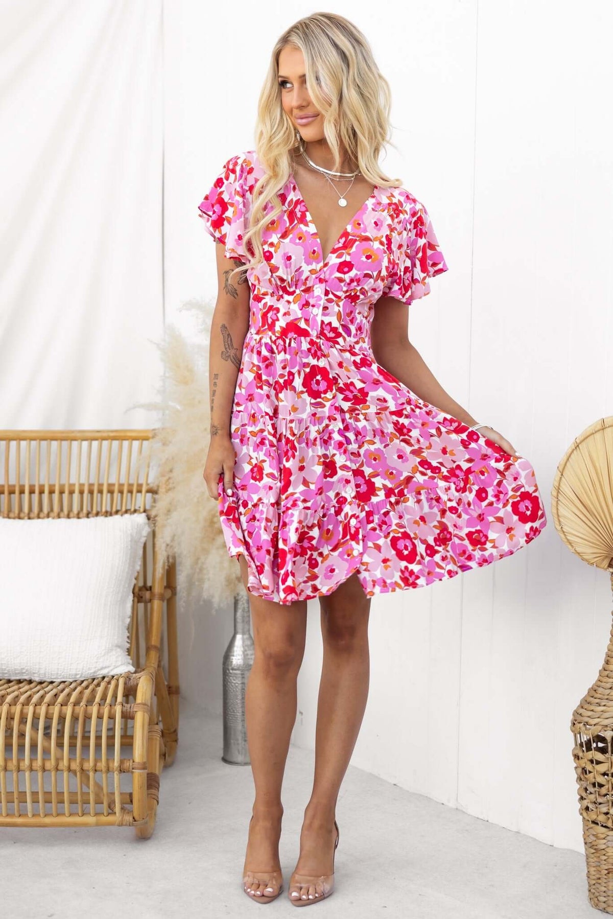 Model wearing a floral pink mini dress with ruffled sleeves, styled for a summer look.