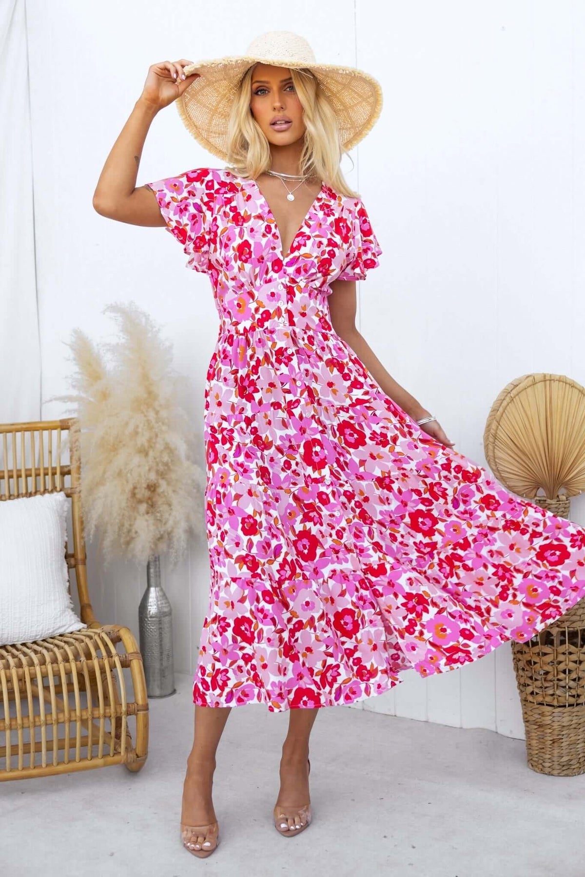 Model wearing a pink floral Hope Filled Midi Dress with a straw hat, showcasing a flowy, vibrant design.