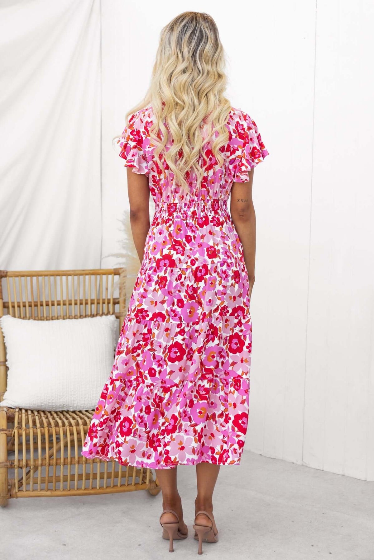 Back view of a model wearing the Hope Filled Midi Dress with floral pattern and shirred waist.