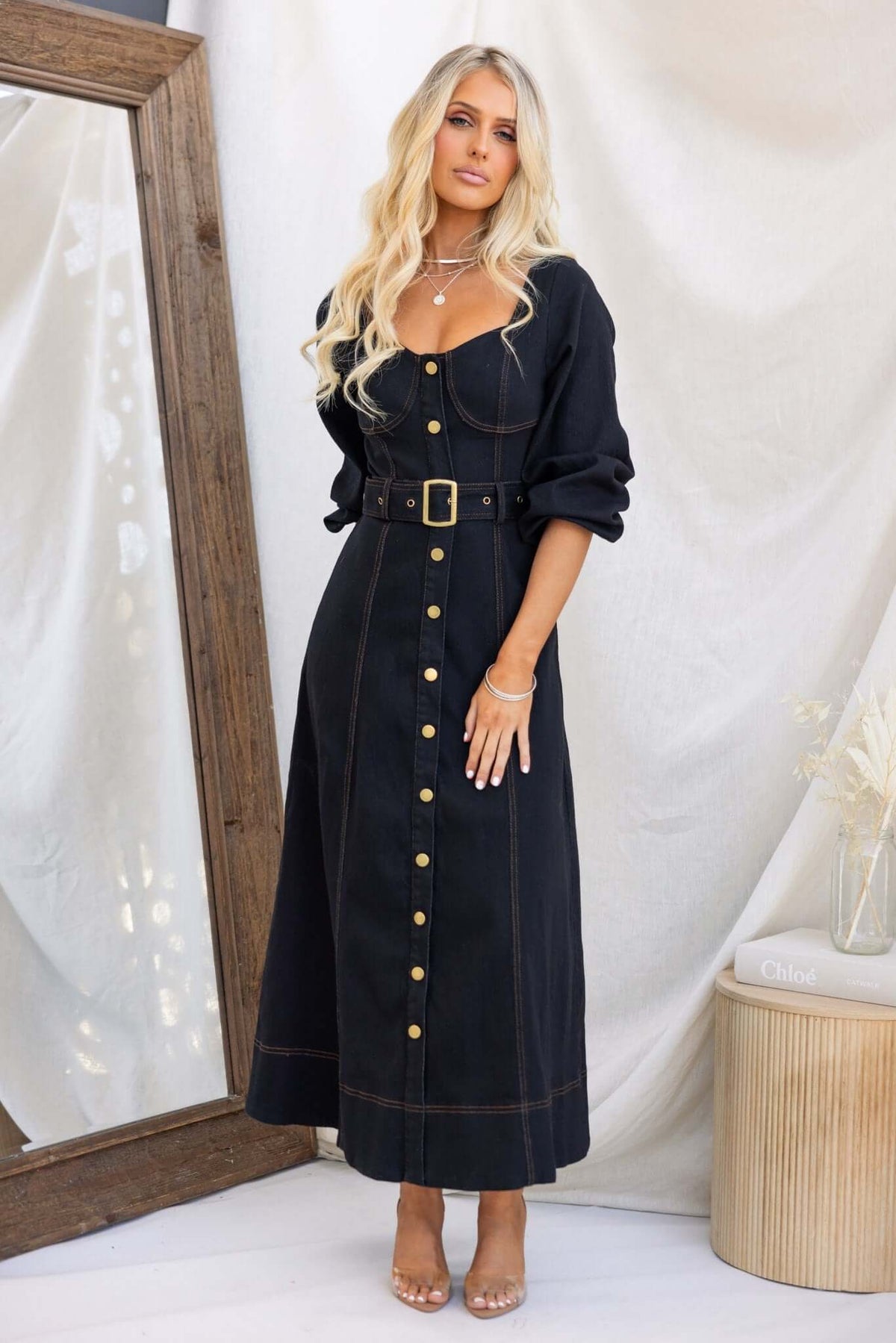 Model wearing a black denim maxi dress with a faux button-up front, elastic sleeves, and a removable belt.
